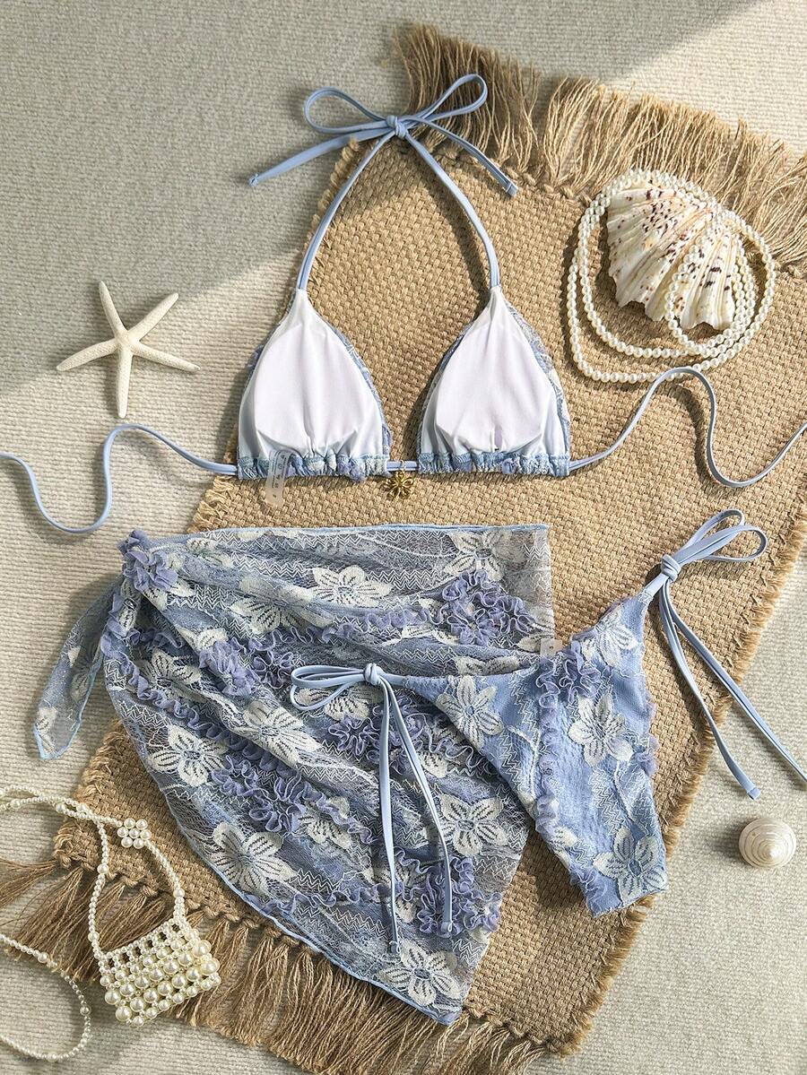 Women's 3-piece blue tropical shell print bikini set featuring a halter bralette top, low-waist tie-side bottom, and a matching sheer mesh cover-up skirt.
