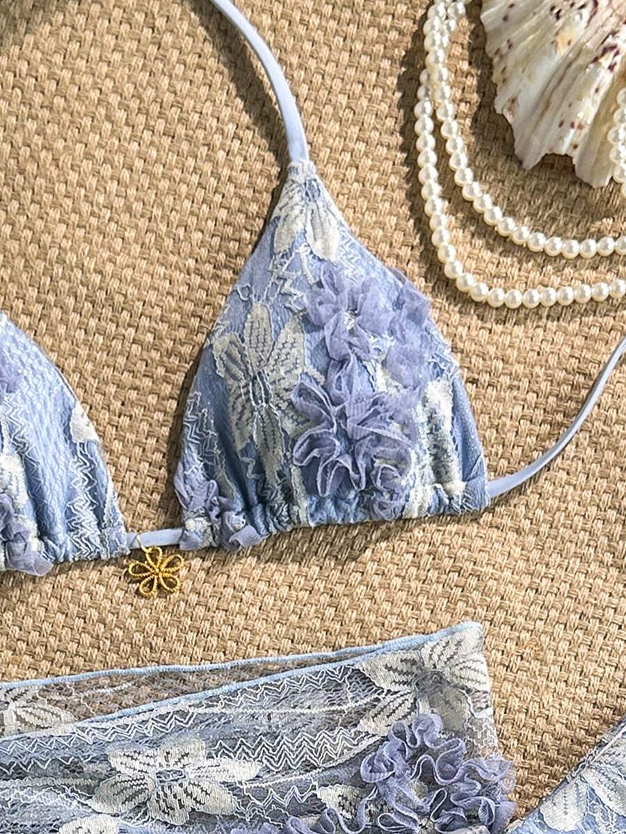 Women's 3-piece blue tropical shell print bikini set featuring a halter bralette top, low-waist tie-side bottom, and a matching sheer mesh cover-up skirt.