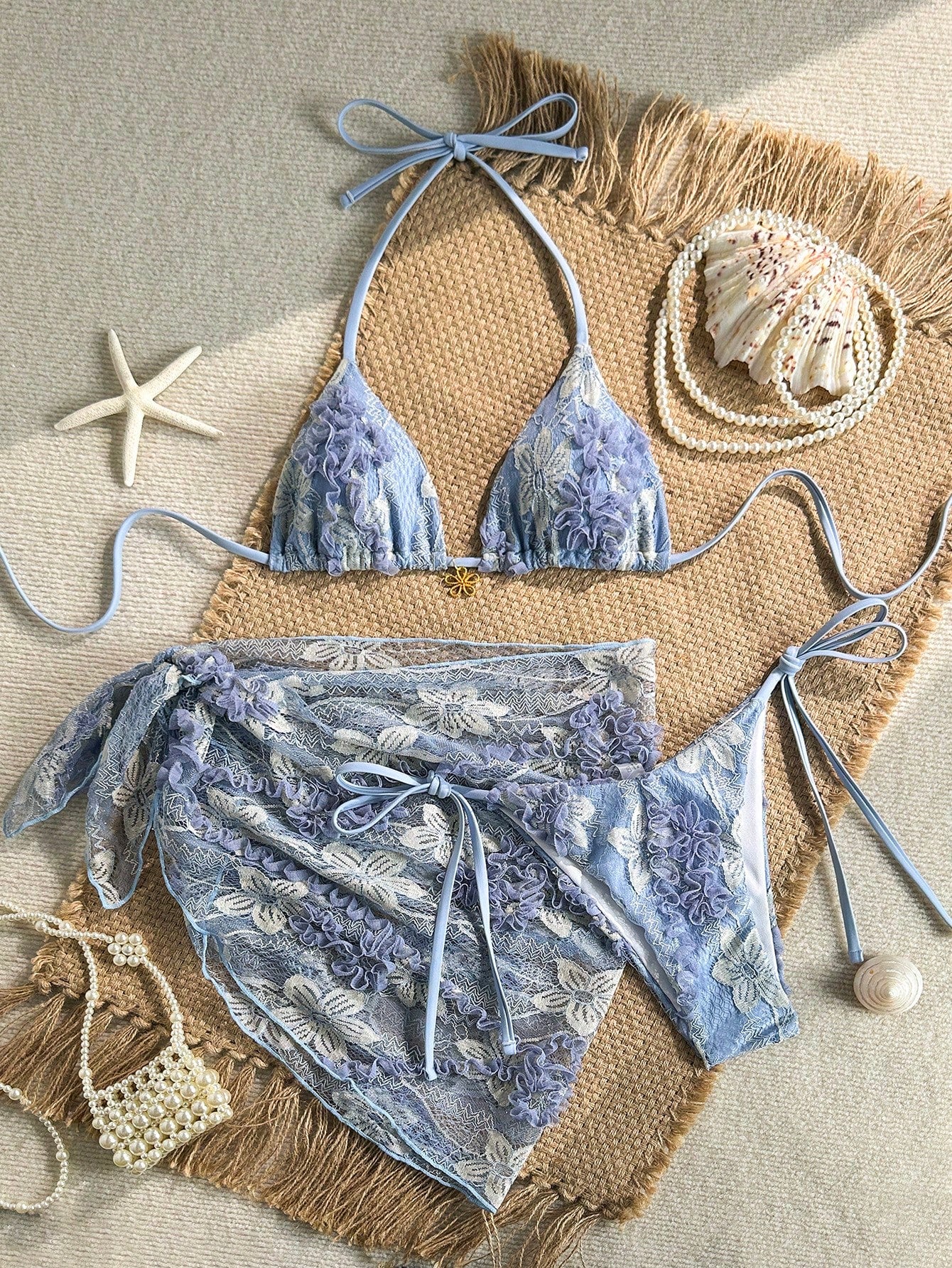 Women's 3-piece blue tropical shell print bikini set featuring a halter bralette top, low-waist tie-side bottom, and a matching sheer mesh cover-up skirt.