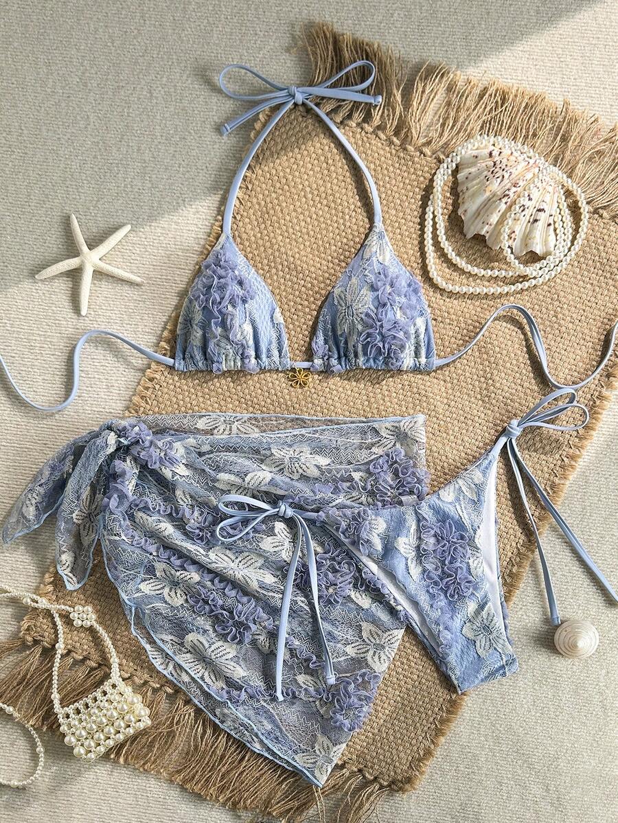 Women's 3-piece blue tropical shell print bikini set featuring a halter bralette top, low-waist tie-side bottom, and a matching sheer mesh cover-up skirt.