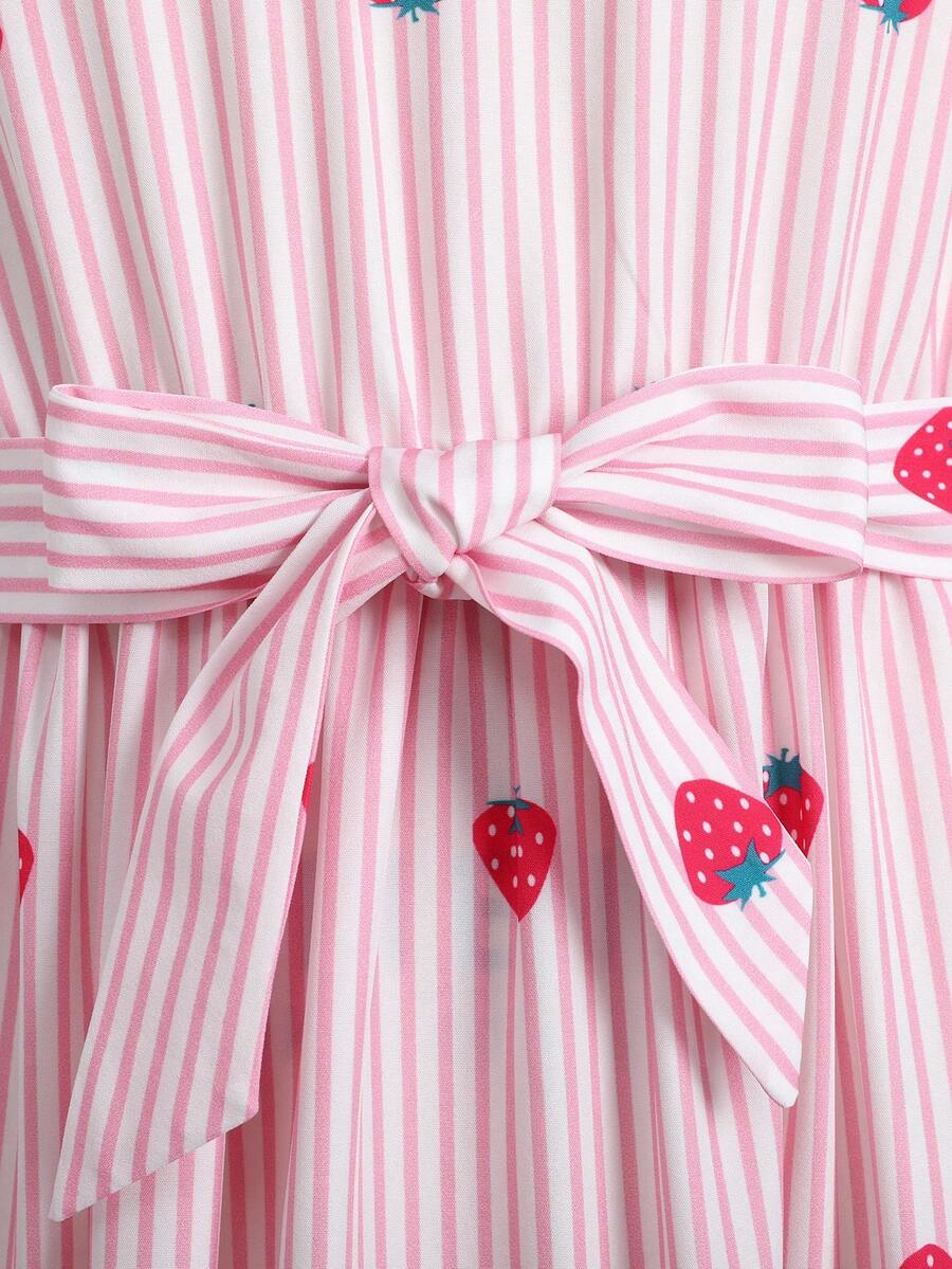 Tween girl wearing a pink long A-line dress featuring a strawberry print, stand collar, flounce short sleeves, and a belted waist with a ruffle hem.