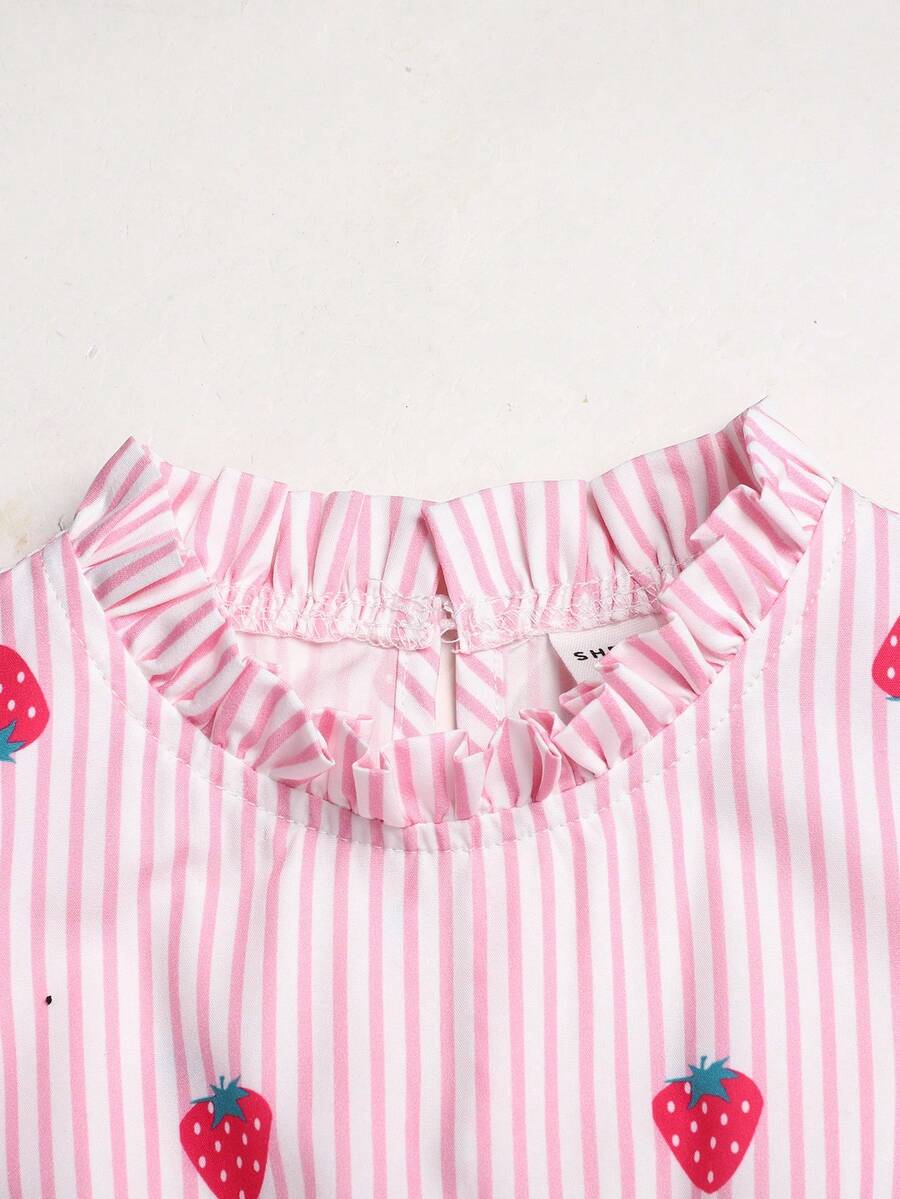 Tween girl wearing a pink long A-line dress featuring a strawberry print, stand collar, flounce short sleeves, and a belted waist with a ruffle hem.