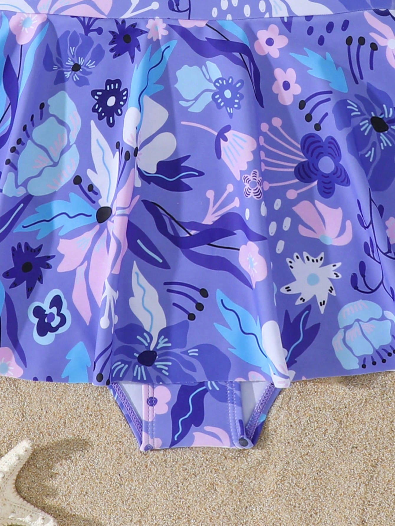 Purple tween girls one-piece swimsuit with graphic striped print, ruffle detail, round neck, and zipper closure for swimming and vacation wear