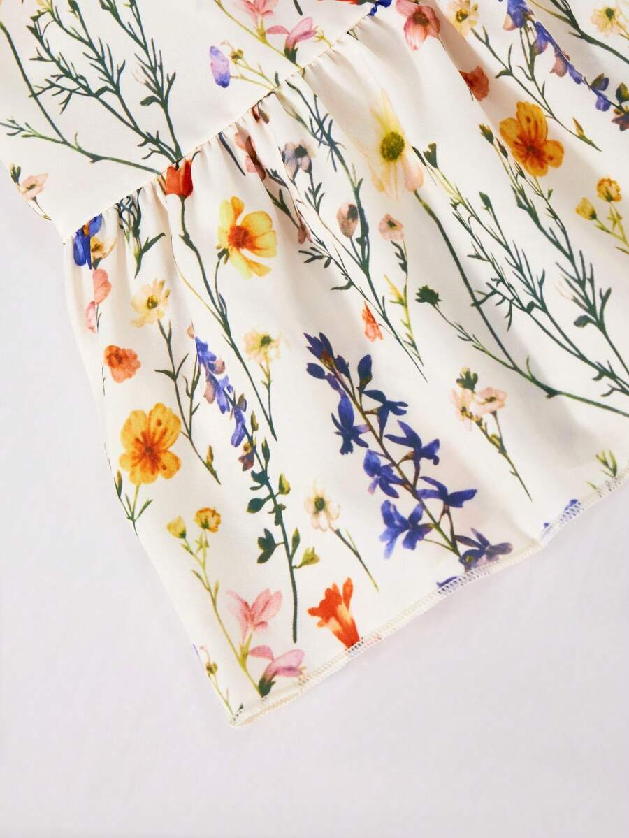 Tween girl wearing an apricot floral print sleeveless mini cami dress featuring spaghetti straps, a shirred high waist, flounce hem, and a bow back detail.