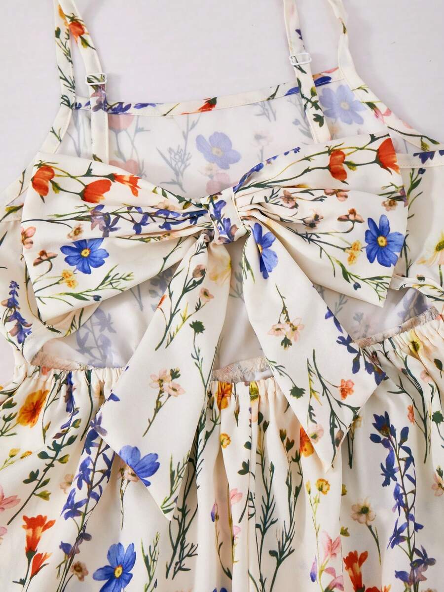 Tween girl wearing an apricot floral print sleeveless mini cami dress featuring spaghetti straps, a shirred high waist, flounce hem, and a bow back detail.