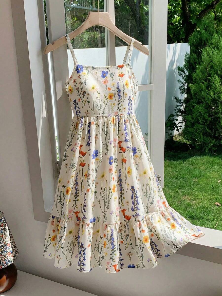 Tween girl wearing an apricot floral print sleeveless mini cami dress featuring spaghetti straps, a shirred high waist, flounce hem, and a bow back detail.