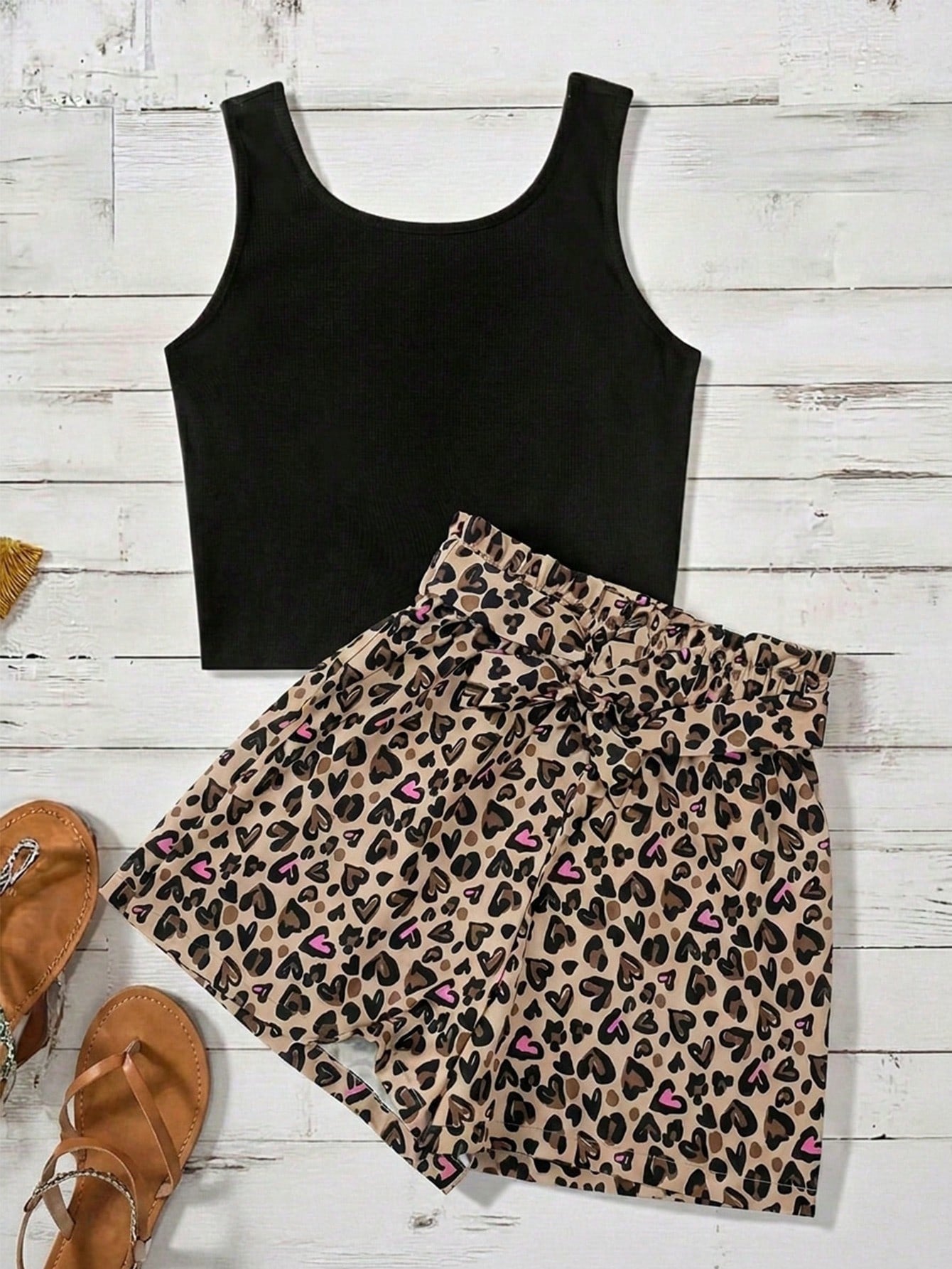 Tween girl wearing a casual 2-piece set featuring a black rib-knit scoop neck tank top and leopard print paperbag waist shorts with a matching belt.
