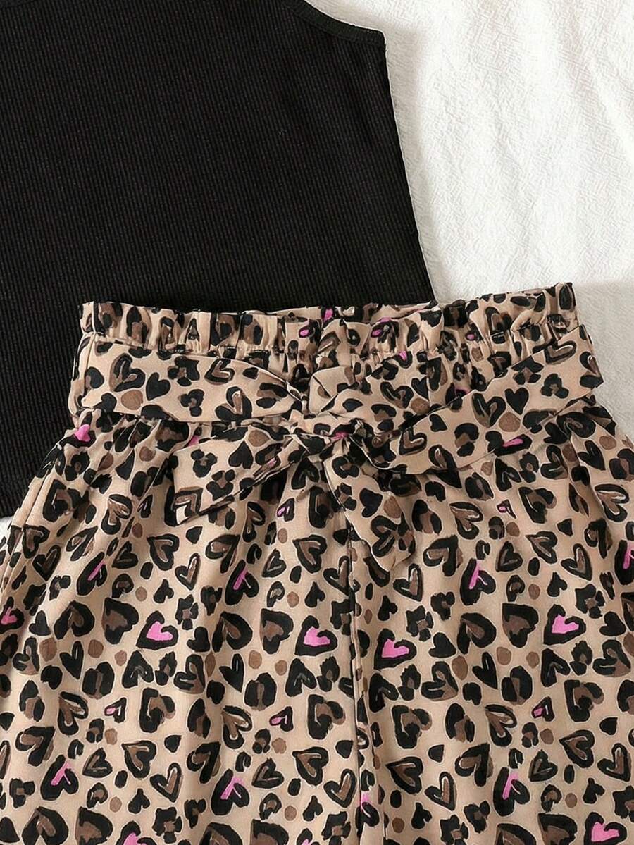 Tween girl wearing a casual 2-piece set featuring a black rib-knit scoop neck tank top and leopard print paperbag waist shorts with a matching belt.