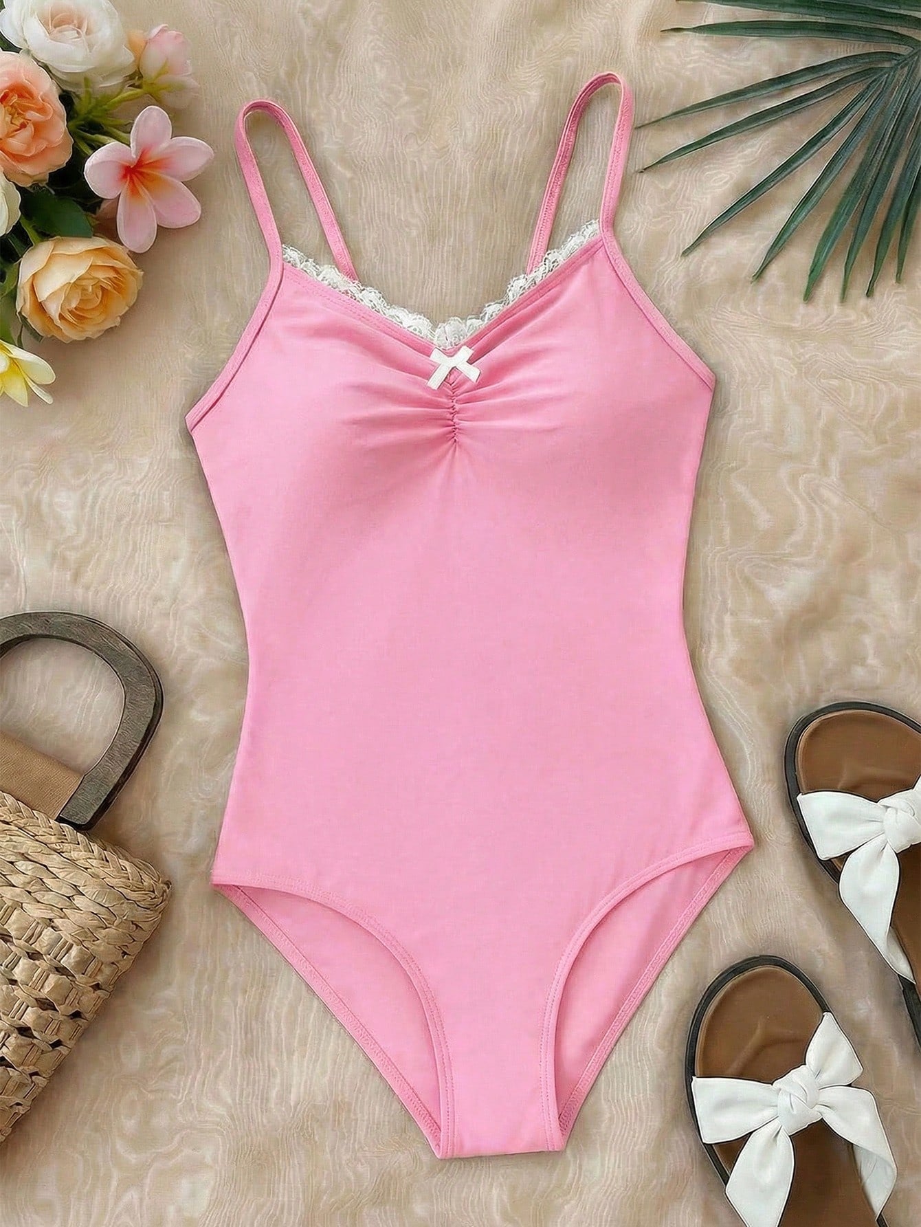 Tween girls' one-piece swimsuit featuring a ruffle splice front, ruched detailing, bow accent, contrast lace trim, and spaghetti straps.