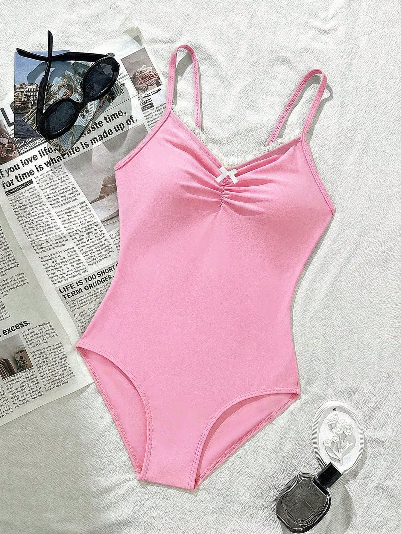 Tween girls' one-piece swimsuit featuring a ruffle splice front, ruched detailing, bow accent, contrast lace trim, and spaghetti straps.
