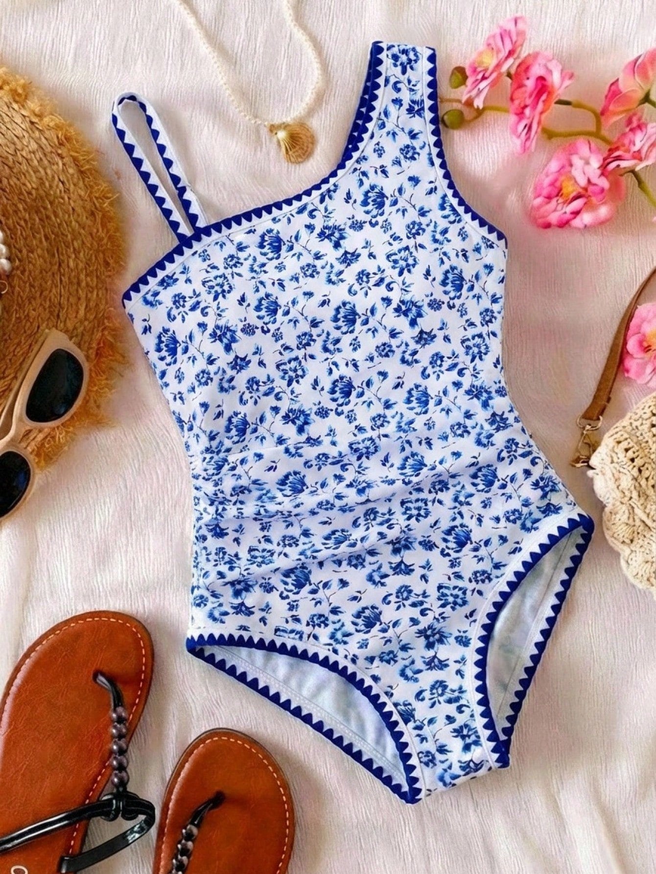 Tween girl one-piece swimsuit in brown polka dot geometric print with asymmetrical neckline, ruffle detail, cut-out design, and fitted mid-waist swim bottom.