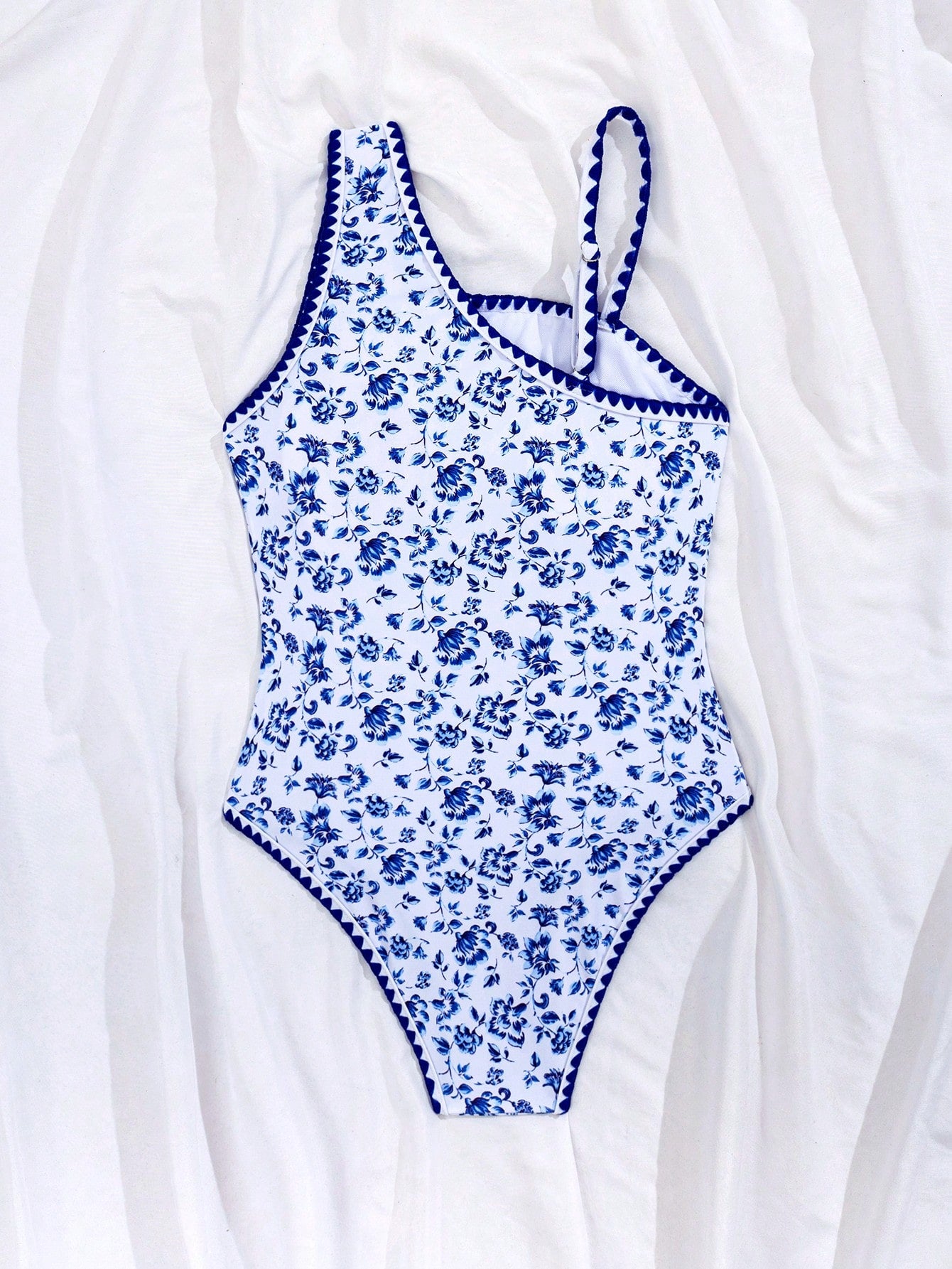 Tween girl one-piece swimsuit in brown polka dot geometric print with asymmetrical neckline, ruffle detail, cut-out design, and fitted mid-waist swim bottom.