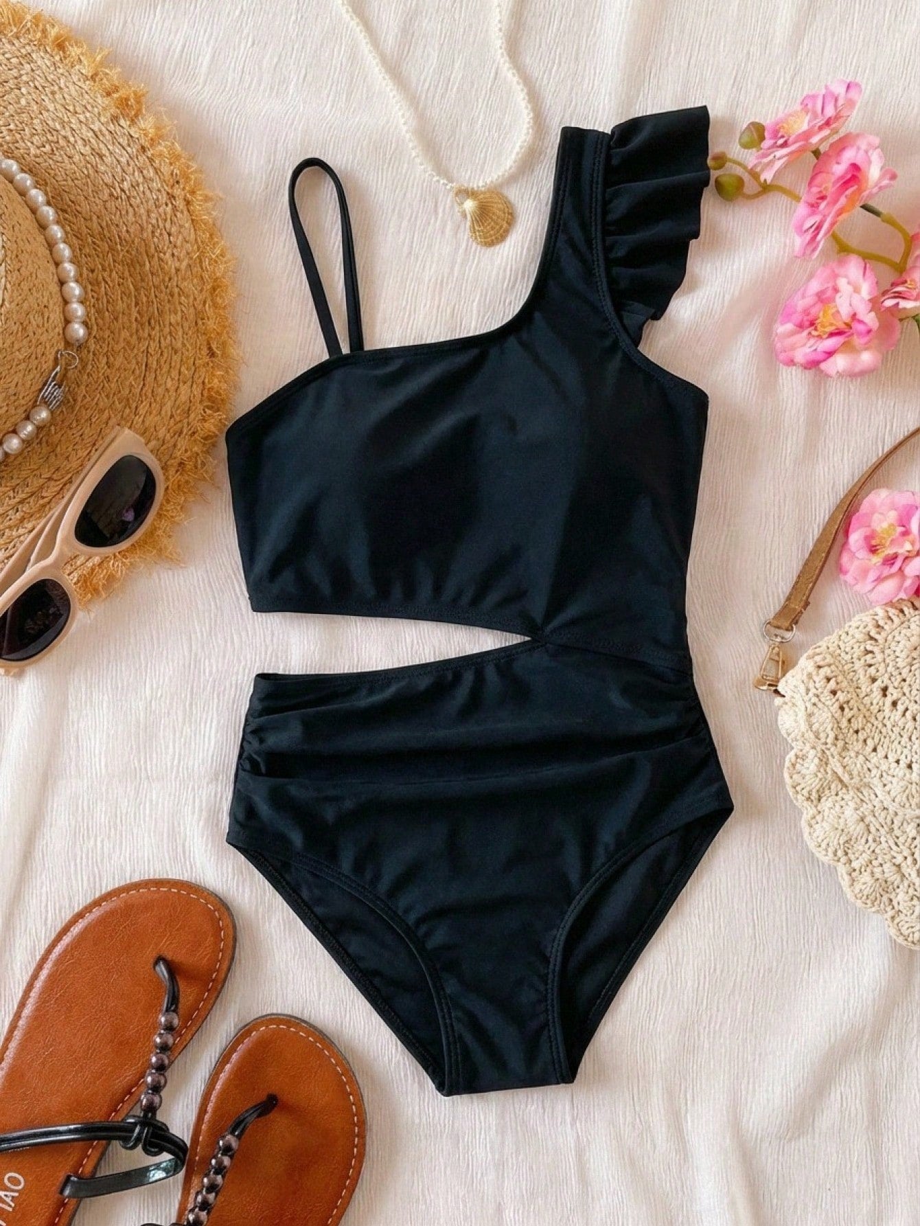 Tween girl one-piece swimsuit in brown polka dot geometric print with asymmetrical neckline, ruffle detail, cut-out design, and fitted mid-waist swim bottom.
