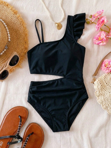 Tween girl one-piece swimsuit in brown polka dot geometric print with asymmetrical neckline, ruffle detail, cut-out design, and fitted mid-waist swim bottom.