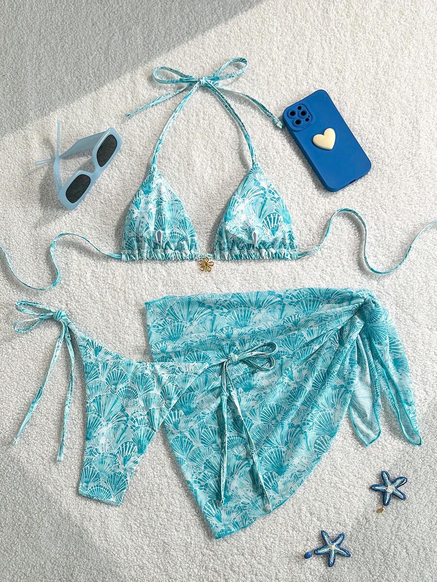 Women's 3-piece blue tropical shell print bikini set featuring a halter bralette top, low-waist tie-side bottom, and a matching sheer mesh cover-up skirt.
