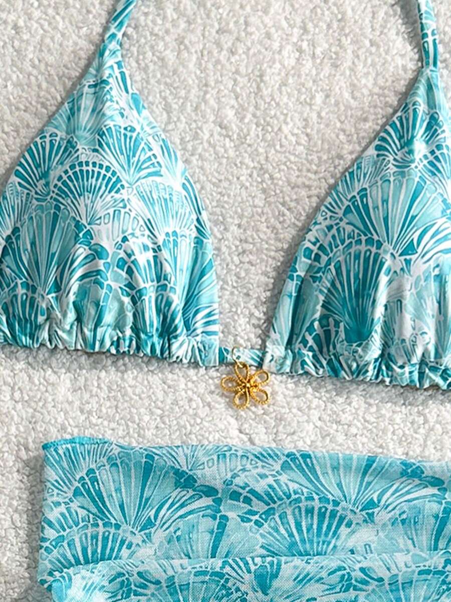 Women's 3-piece blue tropical shell print bikini set featuring a halter bralette top, low-waist tie-side bottom, and a matching sheer mesh cover-up skirt.