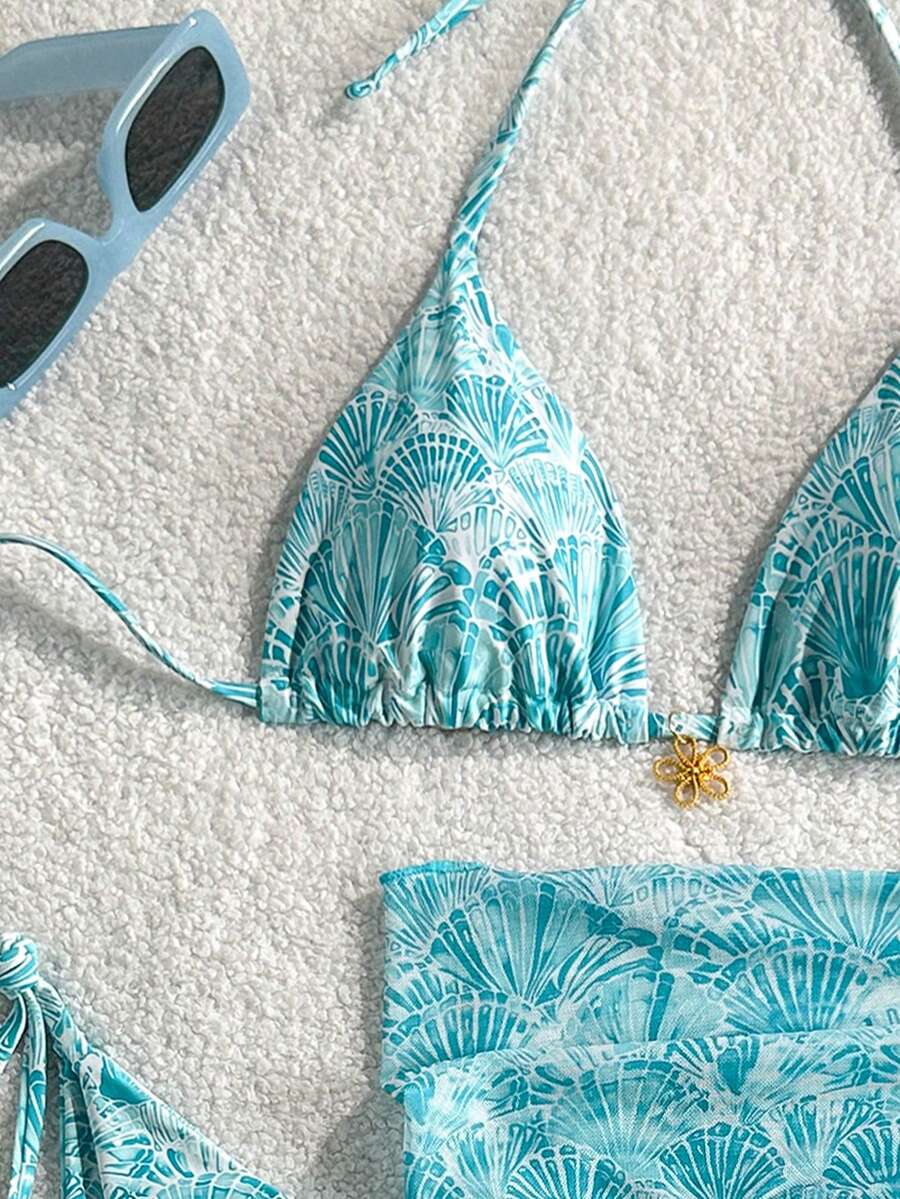 Women's 3-piece blue tropical shell print bikini set featuring a halter bralette top, low-waist tie-side bottom, and a matching sheer mesh cover-up skirt.