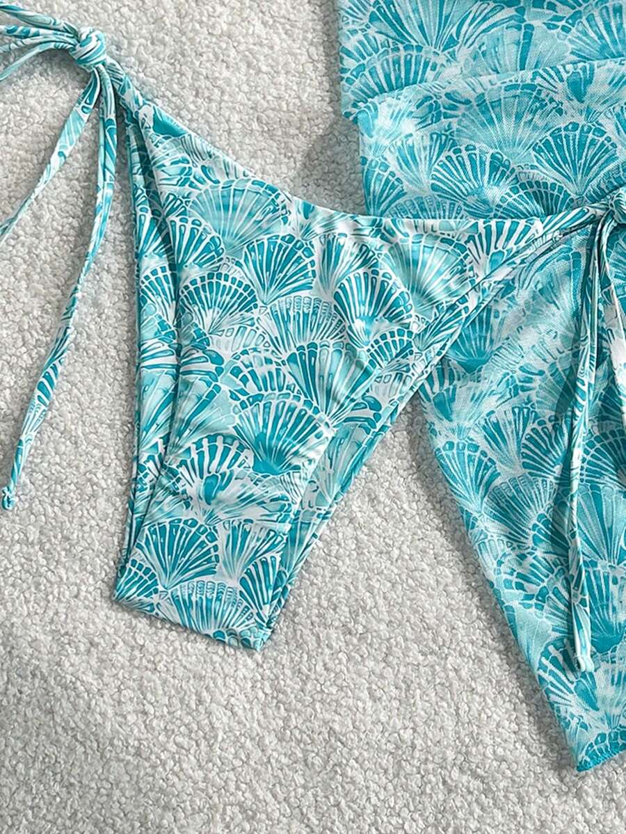 Women's 3-piece blue tropical shell print bikini set featuring a halter bralette top, low-waist tie-side bottom, and a matching sheer mesh cover-up skirt.