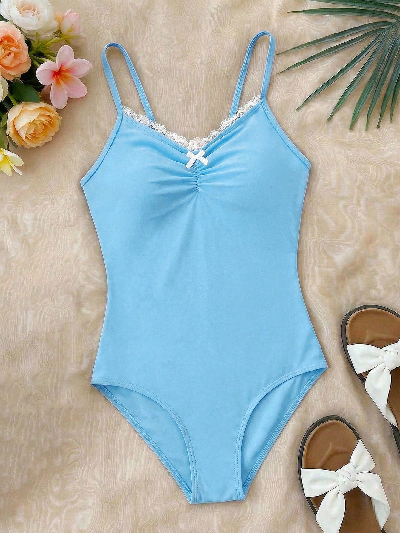 Tween girls' one-piece swimsuit featuring a ruffle splice front, ruched detailing, bow accent, contrast lace trim, and spaghetti straps.