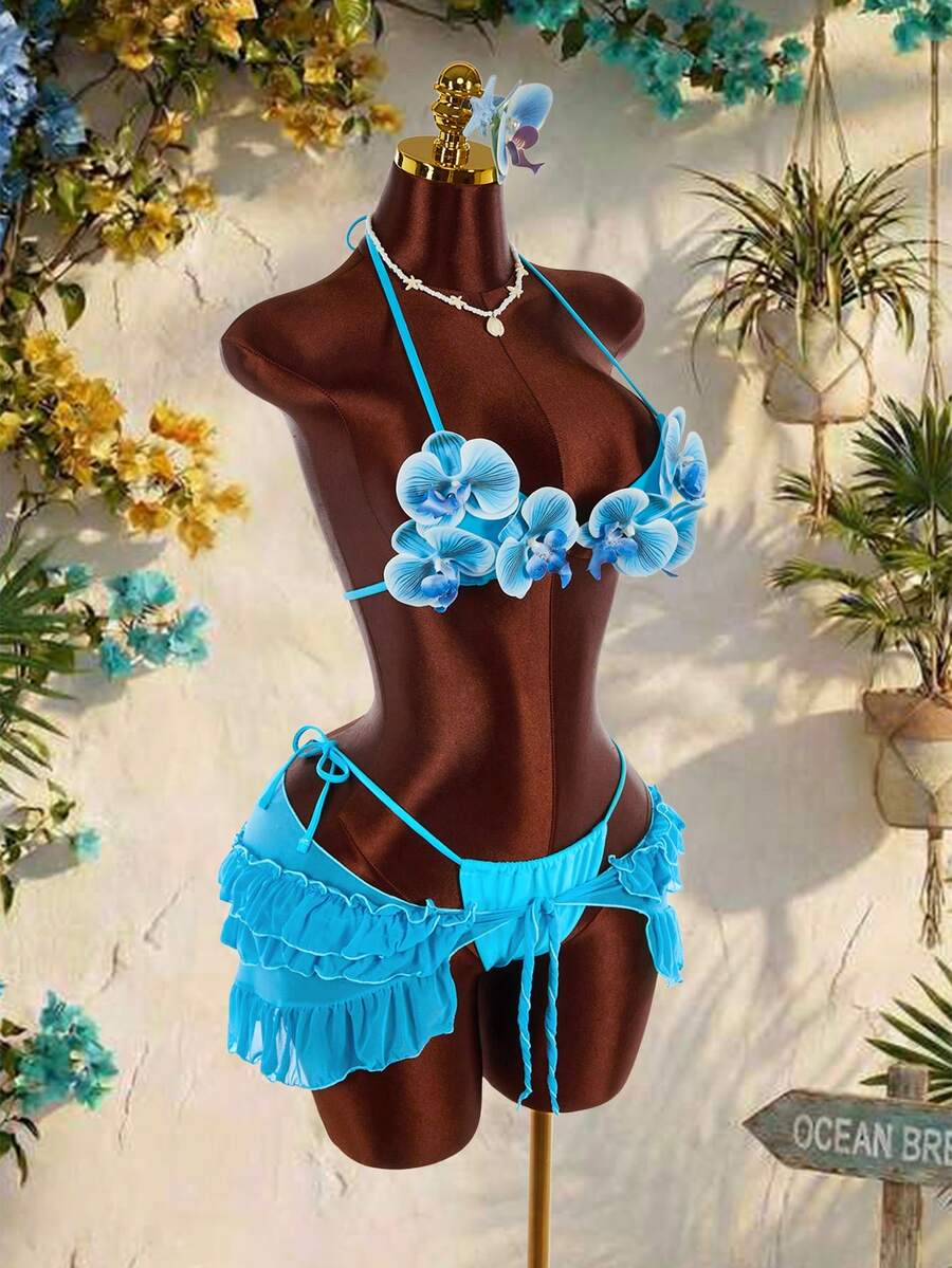 Women's 3-piece blue bikini swimwear set featuring a crop top with 3D rose accents, tie back detail, spaghetti straps, and tie-side bottoms.