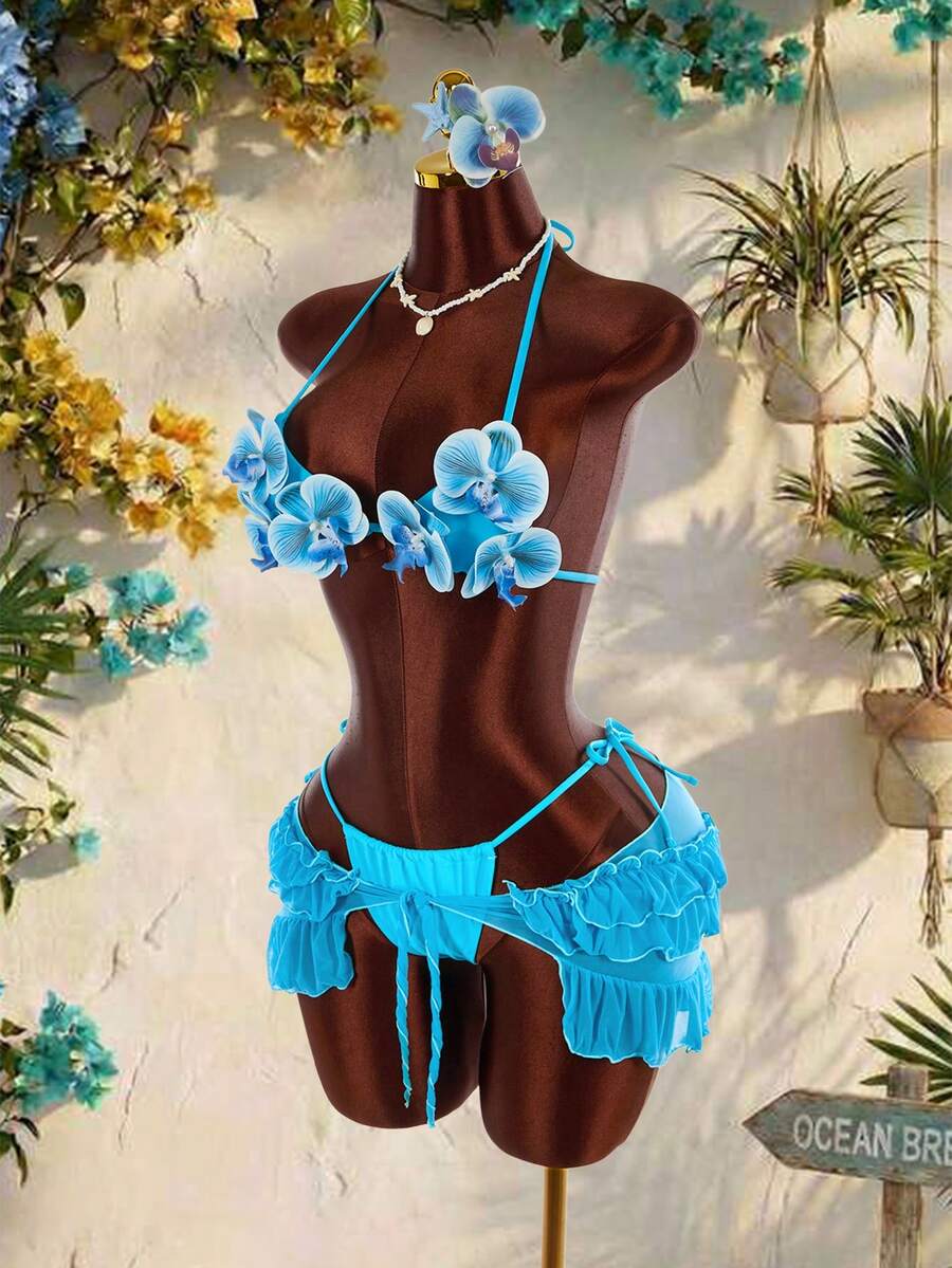 Women's 3-piece blue bikini swimwear set featuring a crop top with 3D rose accents, tie back detail, spaghetti straps, and tie-side bottoms.