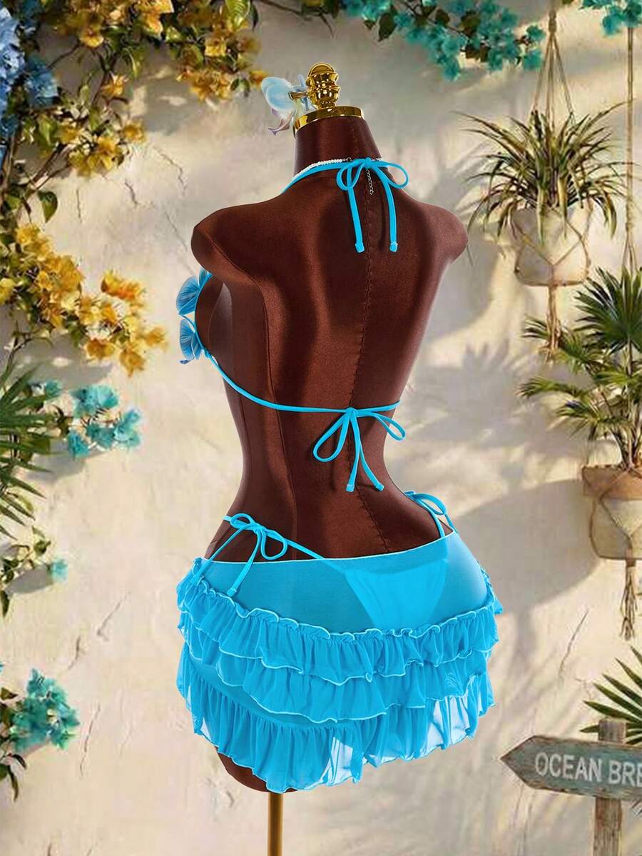 Women's 3-piece blue bikini swimwear set featuring a crop top with 3D rose accents, tie back detail, spaghetti straps, and tie-side bottoms.