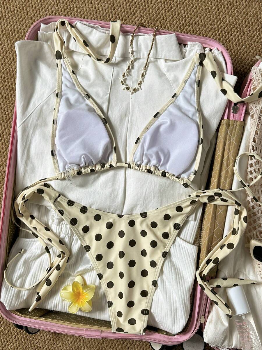 Women's polka dot two-piece bikini set featuring a backless halter top with triangle cups and matching tie-side bottoms.