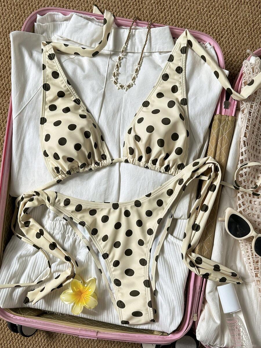 Women's polka dot two-piece bikini set featuring a backless halter top with triangle cups and matching tie-side bottoms.