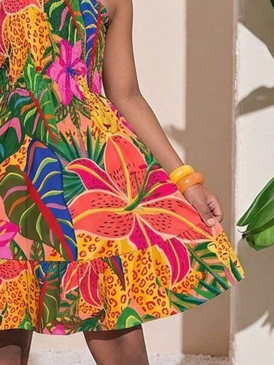 Pink sleeveless tween girls vacation dress with all-over fruit and vegetable print, strap neckline, belted high waist, cut-out detail, and flared ruffle hem.