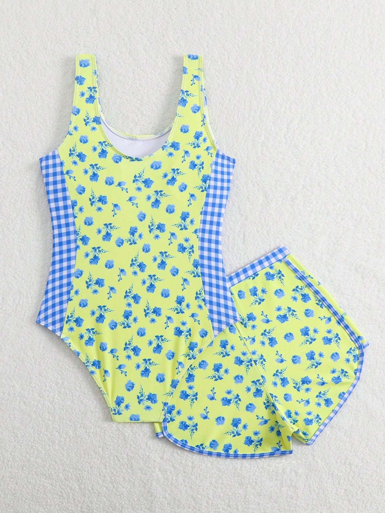 Tween girls 2-piece swimsuit set in black with full floral and plant print, featuring a sleeveless scoop-neck swim top and matching shorts-style bottoms.