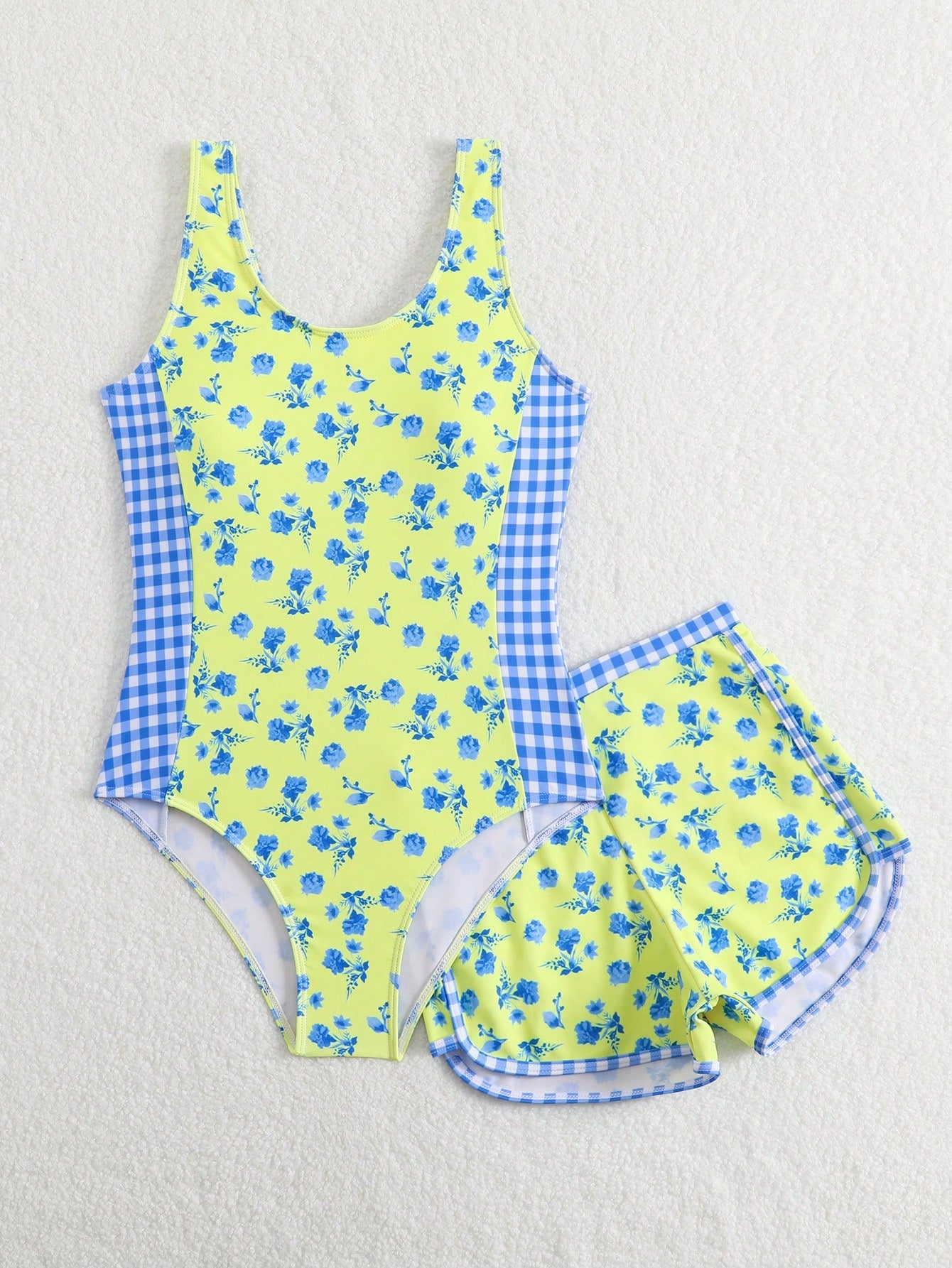 Tween girls 2-piece swimsuit set in black with full floral and plant print, featuring a sleeveless scoop-neck swim top and matching shorts-style bottoms.