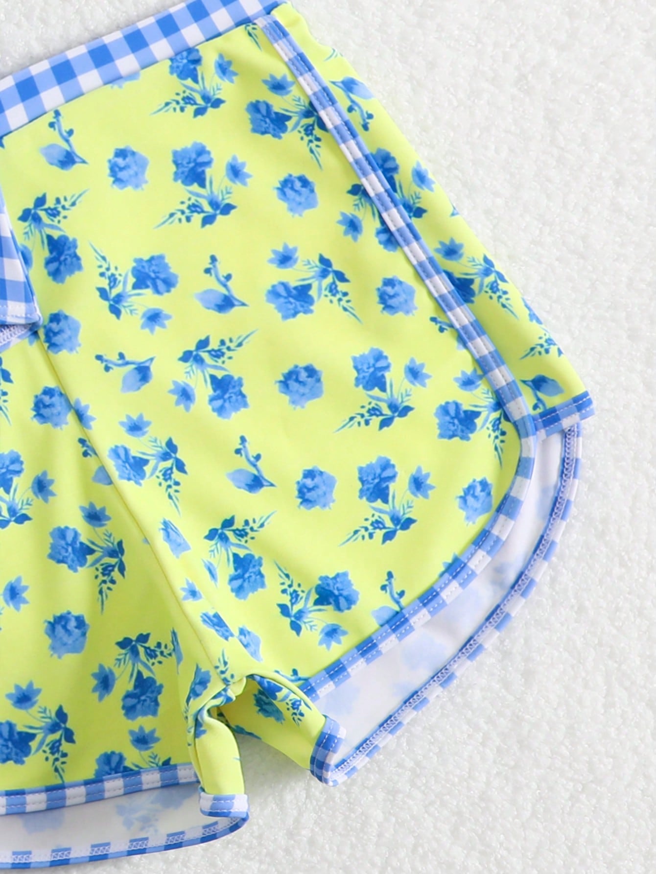 Tween girls 2-piece swimsuit set in black with full floral and plant print, featuring a sleeveless scoop-neck swim top and matching shorts-style bottoms.