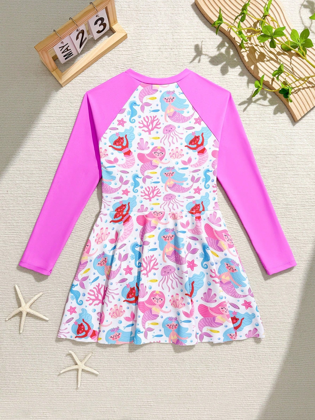 Tween girls one-piece rash guard swimsuit with long sleeves, high neck, front zipper, and ocean shell graphic print in a fitted style for beach, swimming, and vacation wear.