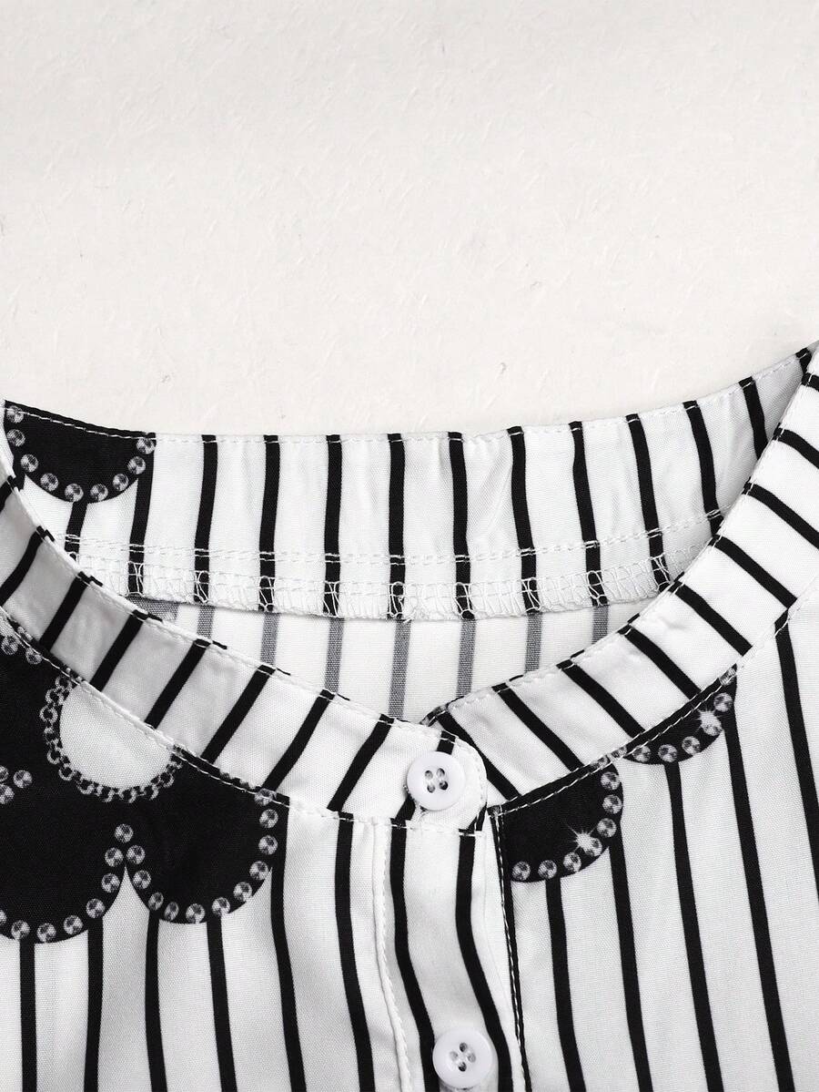 Tween girl wearing a black striped smock shirt dress with flounce half sleeves, a stand collar, and a ruffled hem.