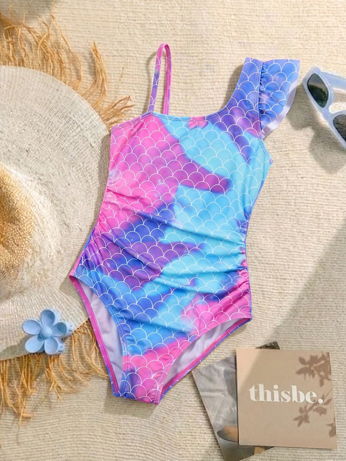 Tween girl one-piece swimsuit in brown polka dot geometric print with asymmetrical neckline, ruffle detail, cut-out design, and fitted mid-waist swim bottom.