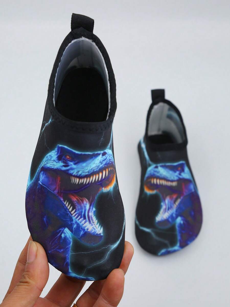Multicolor boys water shoes featuring a cartoon Tyrannosaurus Rex print, breathable Lycra upper, slip-on stretch collar, and flexible non-slip rubber outsole.