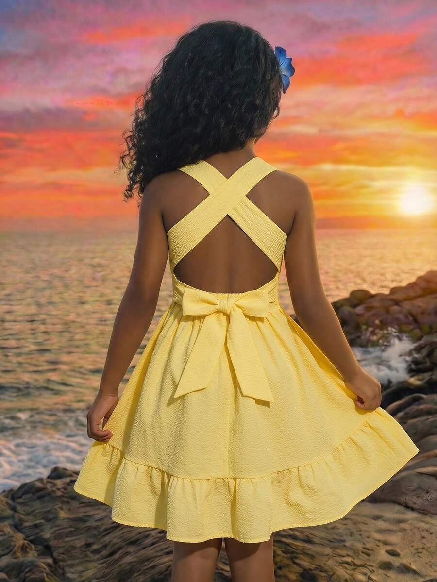 Pink sleeveless tween girls vacation dress with all-over fruit and vegetable print, strap neckline, belted high waist, cut-out detail, and flared ruffle hem.