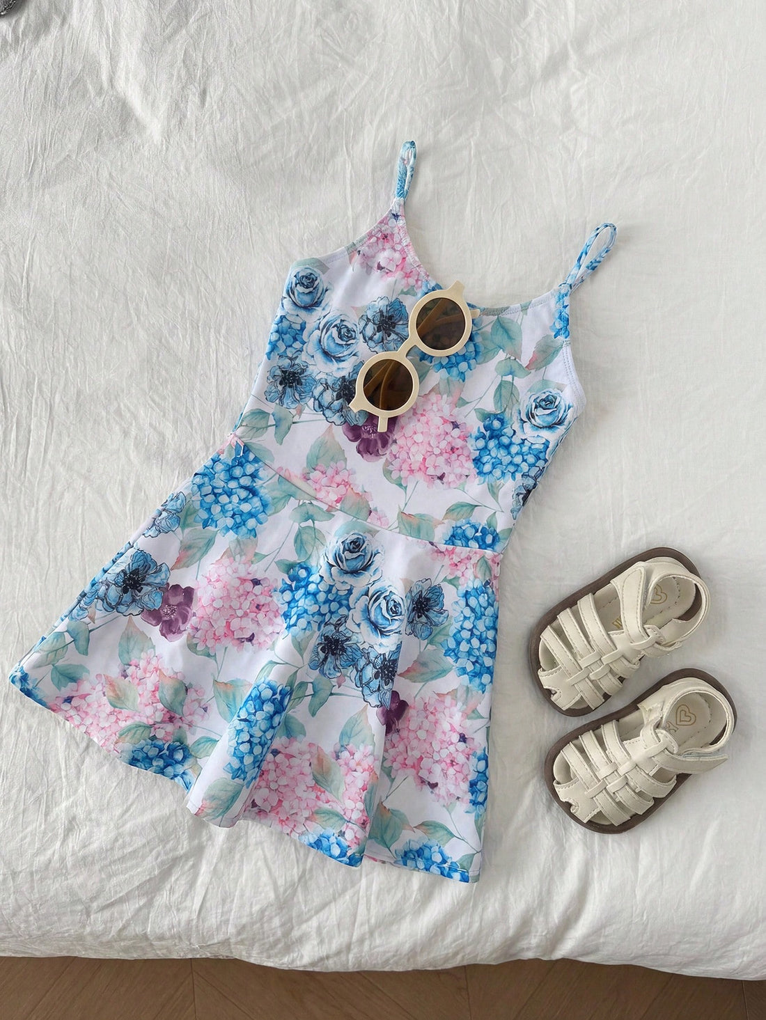 Baby blue graphic one-piece swimsuit for tween girls with spaghetti straps, asymmetrical detail, fitted shape, and vacation beachwear style