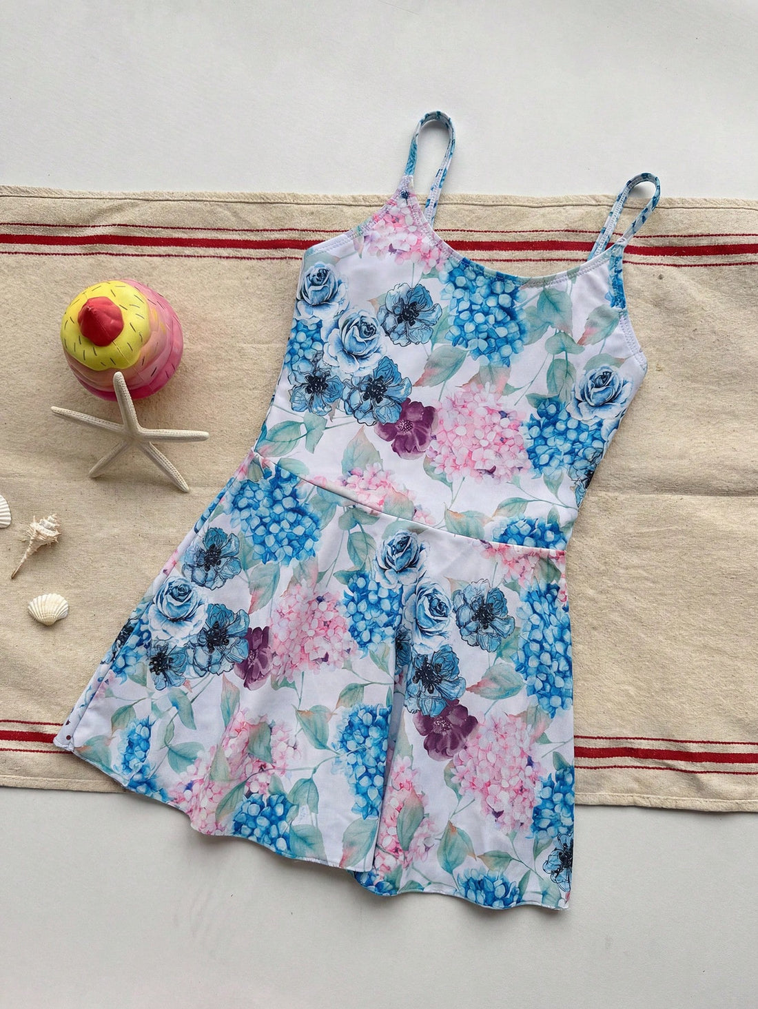 Baby blue graphic one-piece swimsuit for tween girls with spaghetti straps, asymmetrical detail, fitted shape, and vacation beachwear style