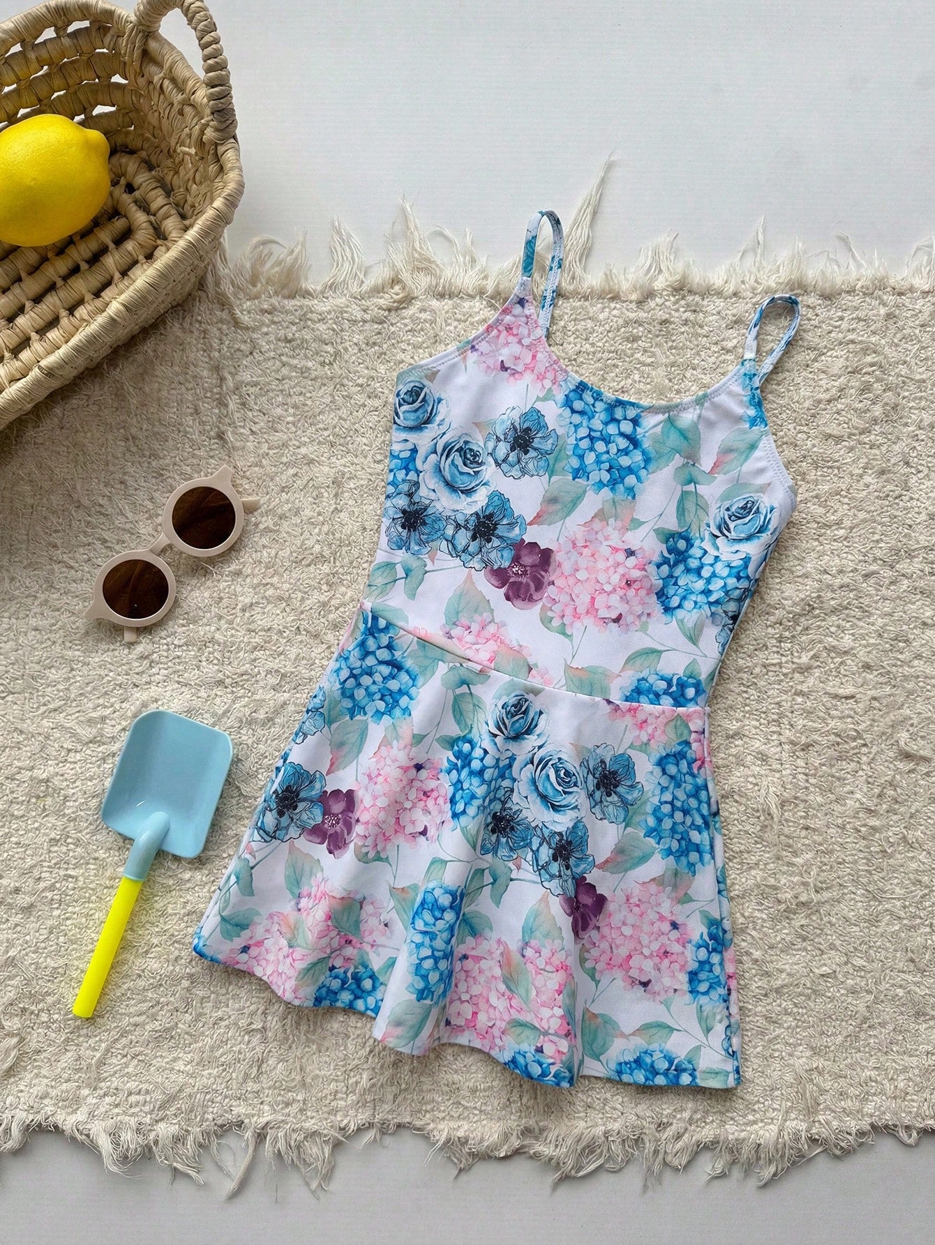 Baby blue graphic one-piece swimsuit for tween girls with spaghetti straps, asymmetrical detail, fitted shape, and vacation beachwear style
