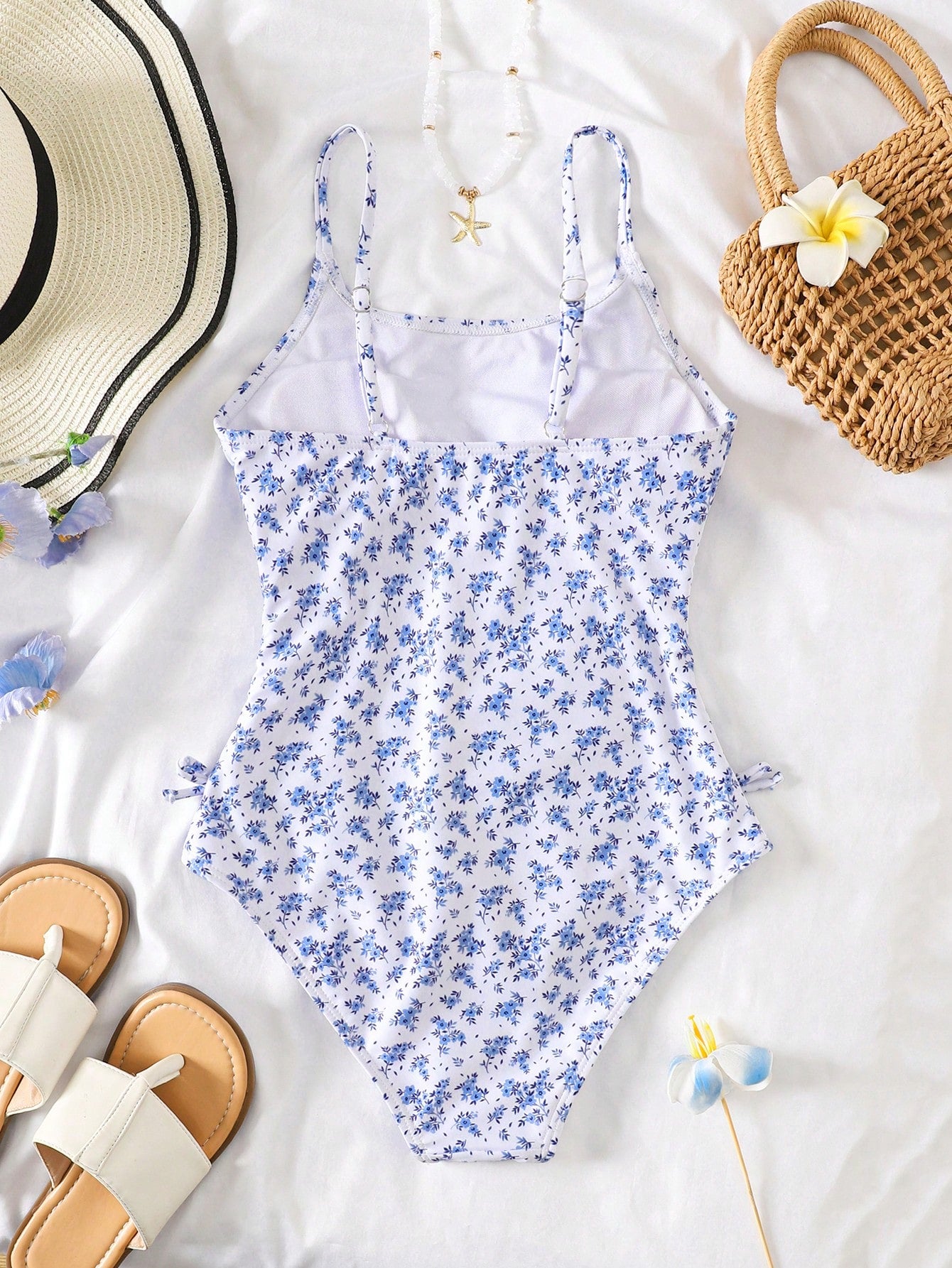Baby blue floral ruffle one-piece swimsuit for tween girls with bow decor, spaghetti straps, all-over print, and fitted vacation beachwear style.