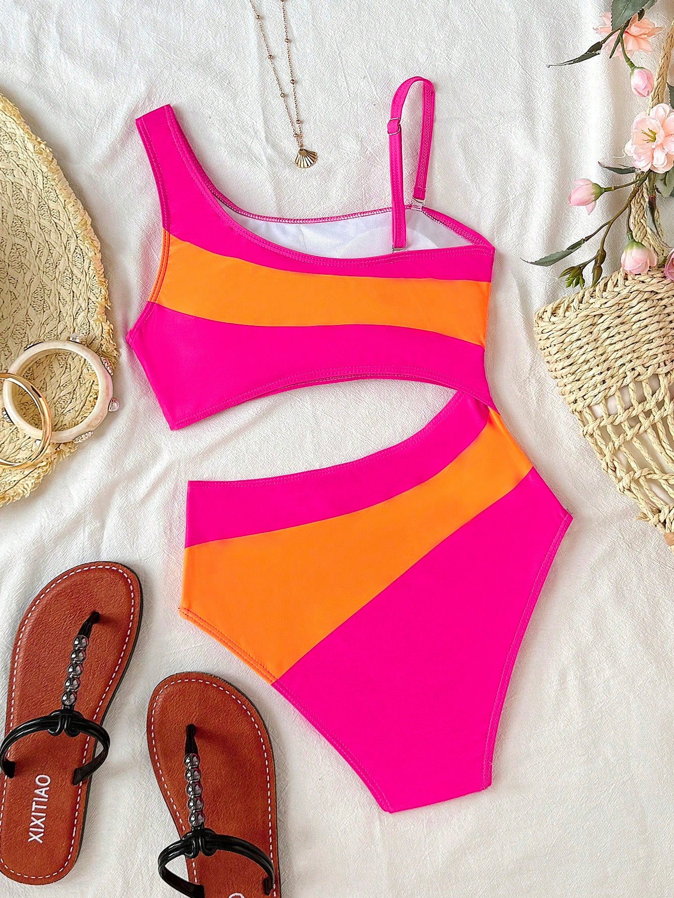 Tween girl one-piece swimsuit in brown polka dot geometric print with asymmetrical neckline, ruffle detail, cut-out design, and fitted mid-waist swim bottom.