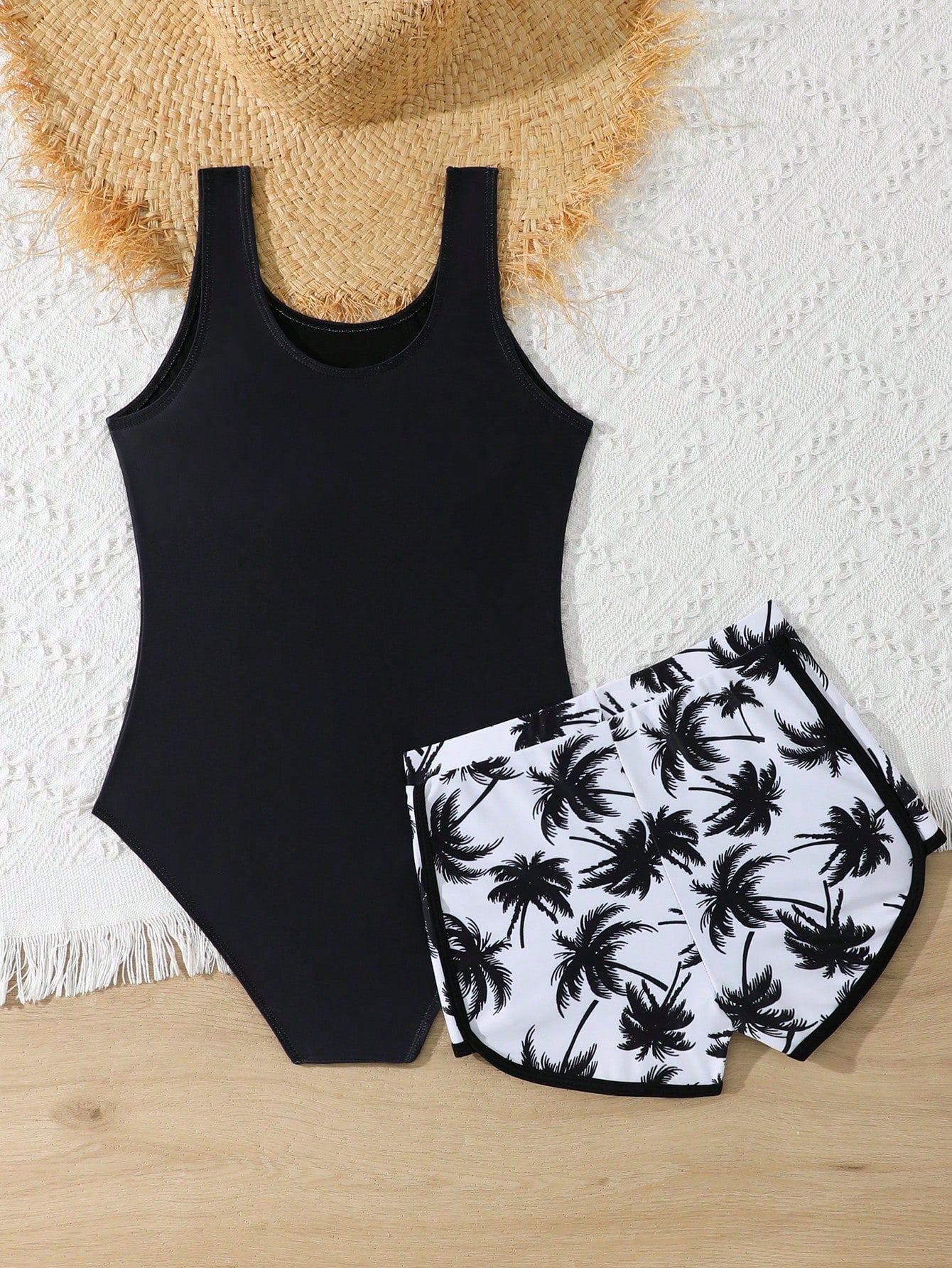 Tween girls 2-piece swimsuit set in black with full floral and plant print, featuring a sleeveless scoop-neck swim top and matching shorts-style bottoms.