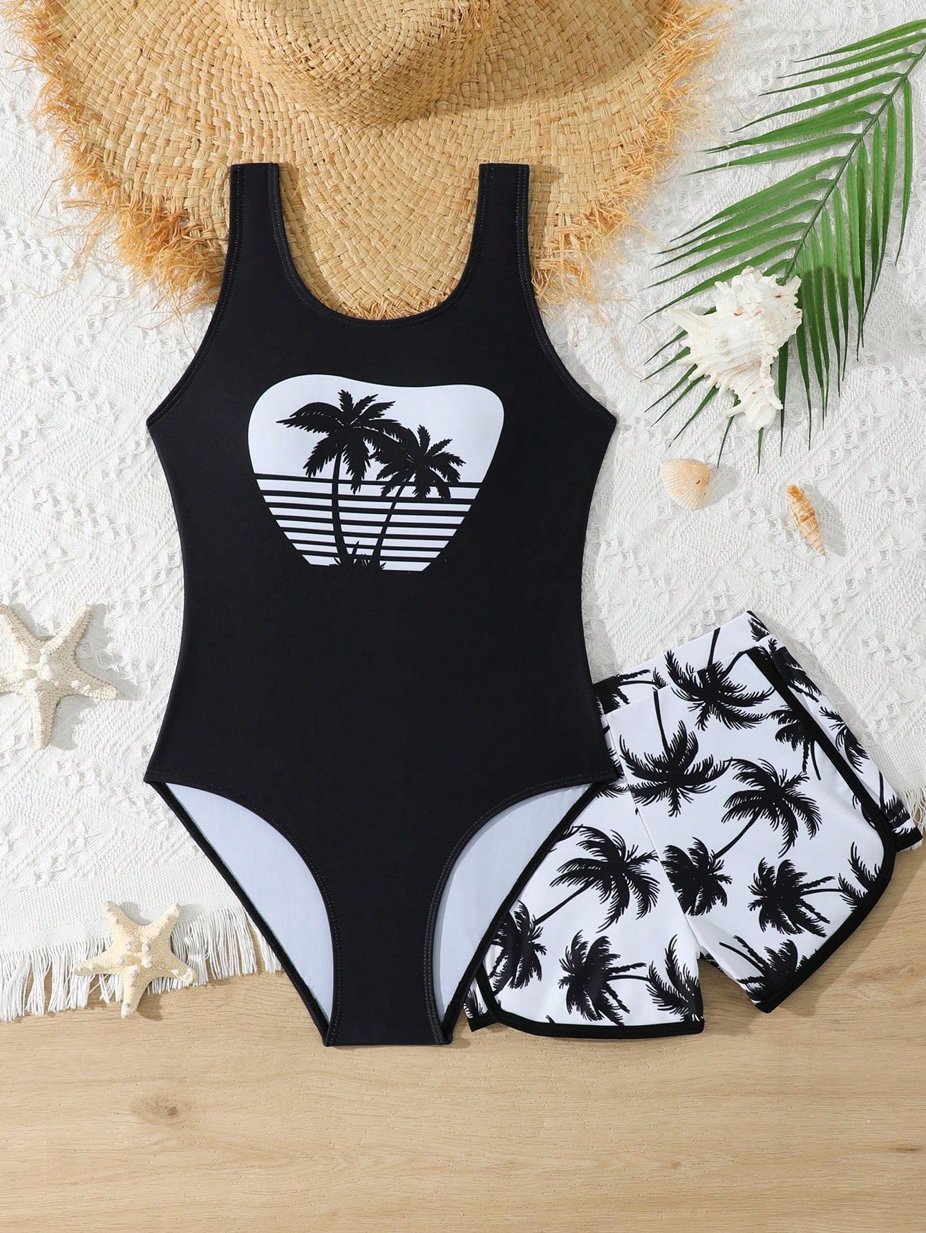 Tween girls 2-piece swimsuit set in black with full floral and plant print, featuring a sleeveless scoop-neck swim top and matching shorts-style bottoms.