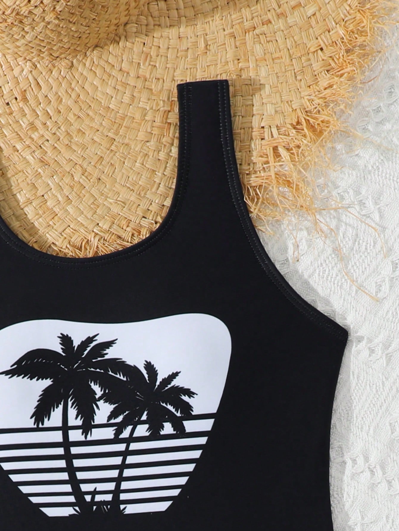 Tween girls 2-piece swimsuit set in black with full floral and plant print, featuring a sleeveless scoop-neck swim top and matching shorts-style bottoms.