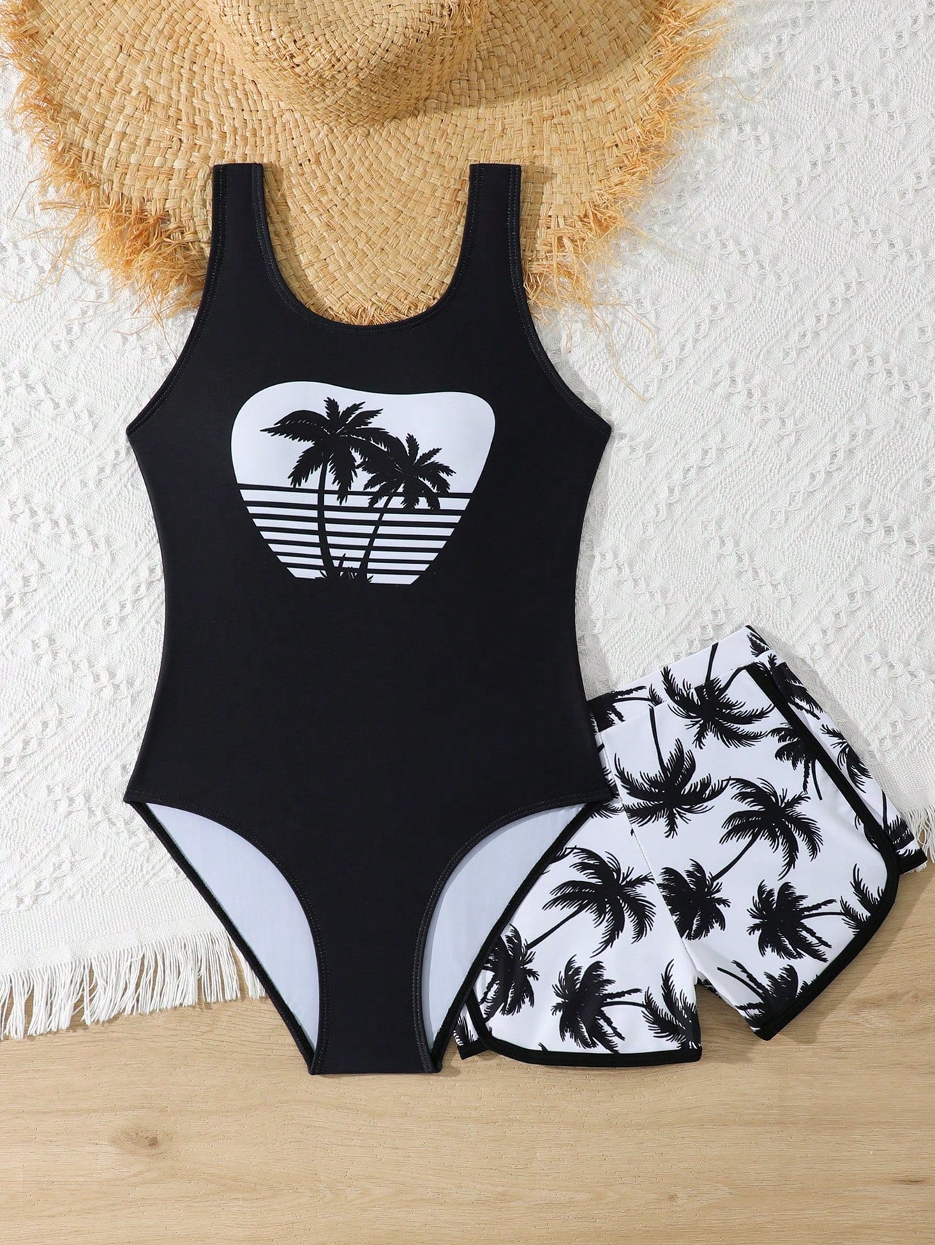 Tween girls 2-piece swimsuit set in black with full floral and plant print, featuring a sleeveless scoop-neck swim top and matching shorts-style bottoms.