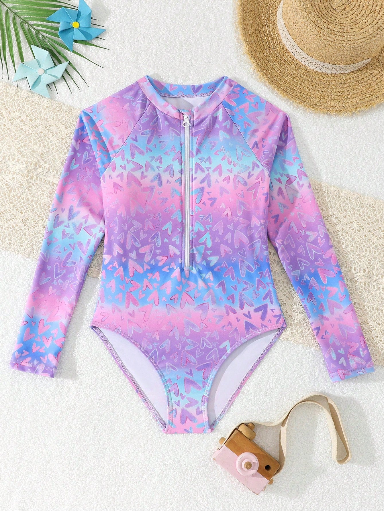 Tween girls one-piece rash guard swimsuit with long sleeves, high neck, front zipper, and ocean shell graphic print in a fitted style for beach, swimming, and vacation wear.