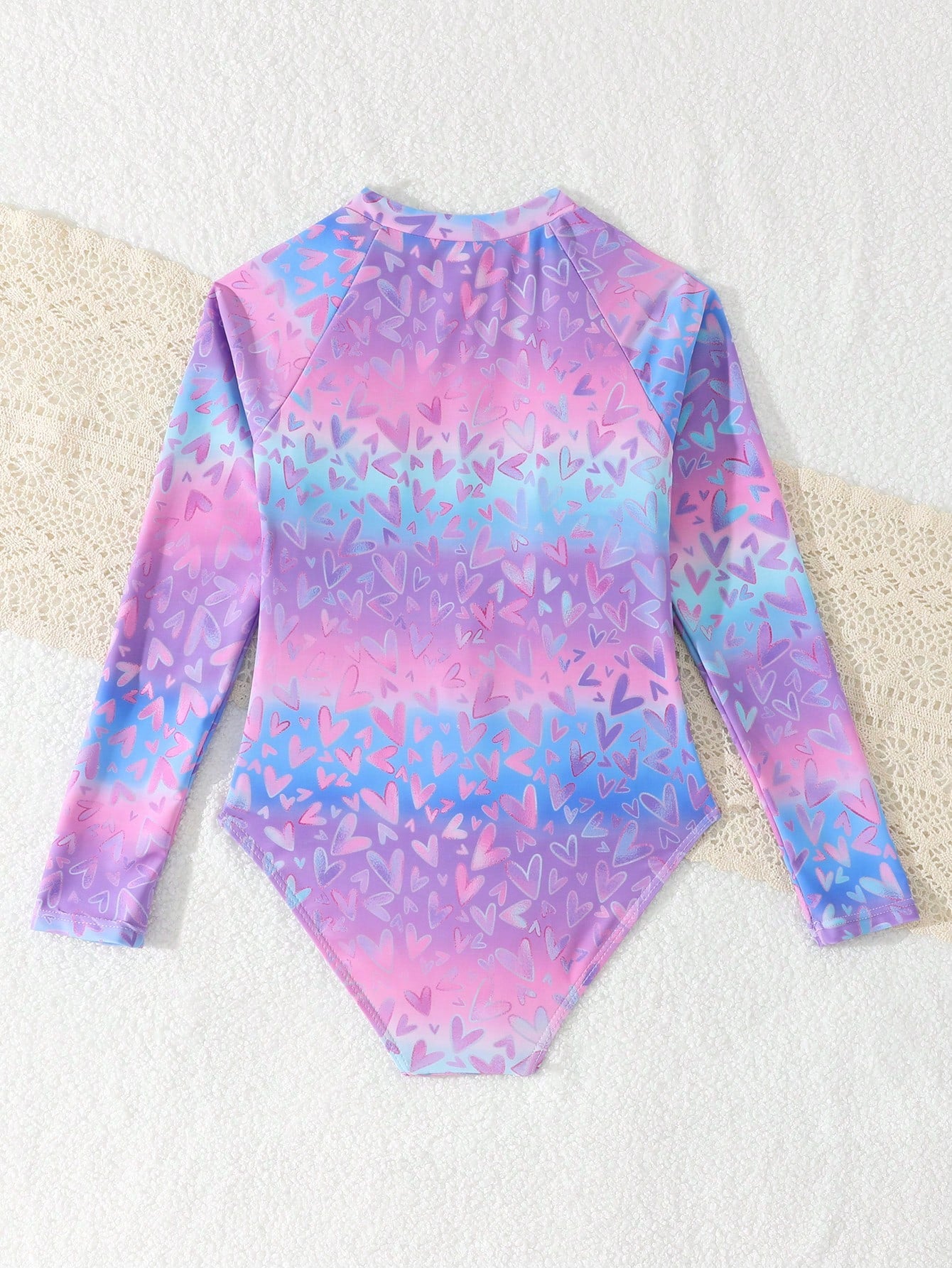 Tween girls one-piece rash guard swimsuit with long sleeves, high neck, front zipper, and ocean shell graphic print in a fitted style for beach, swimming, and vacation wear.