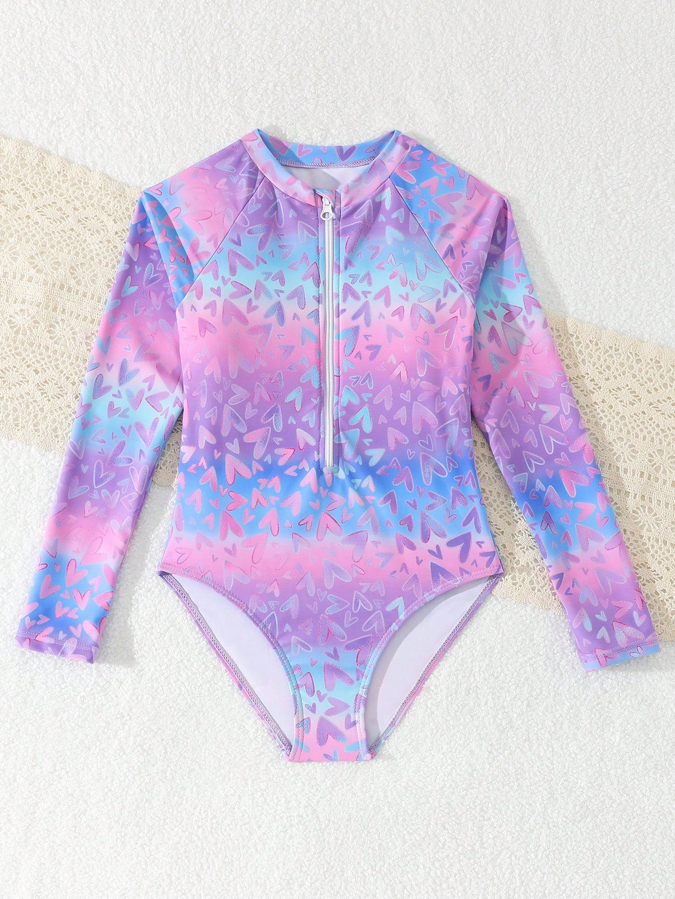Tween girls one-piece rash guard swimsuit with long sleeves, high neck, front zipper, and ocean shell graphic print in a fitted style for beach, swimming, and vacation wear.