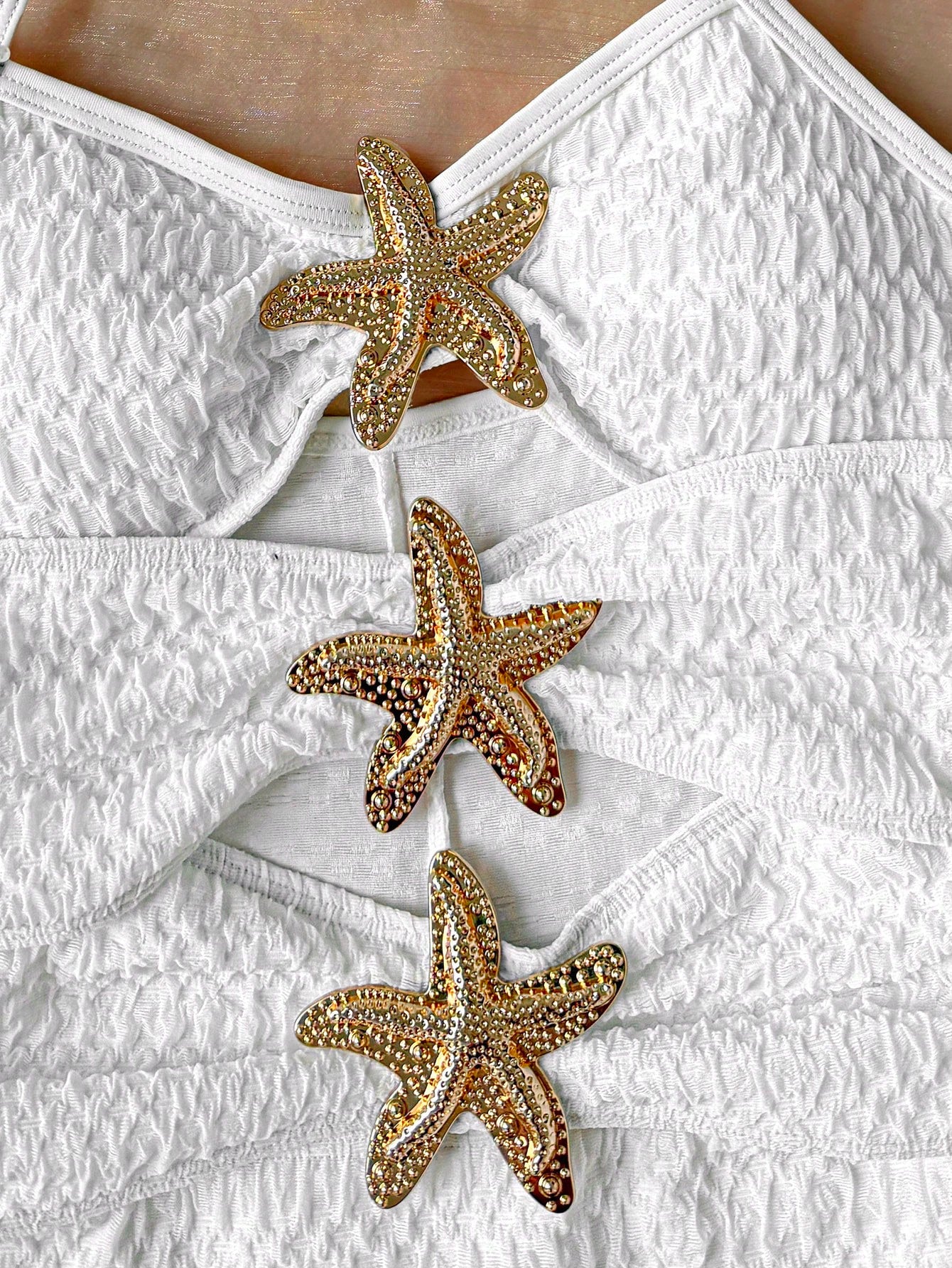 Apricot one-piece swimsuit for tween girls with a halter neckline, ruffle trim, textured knit fabric, fitted shape, and starfish metal decor.